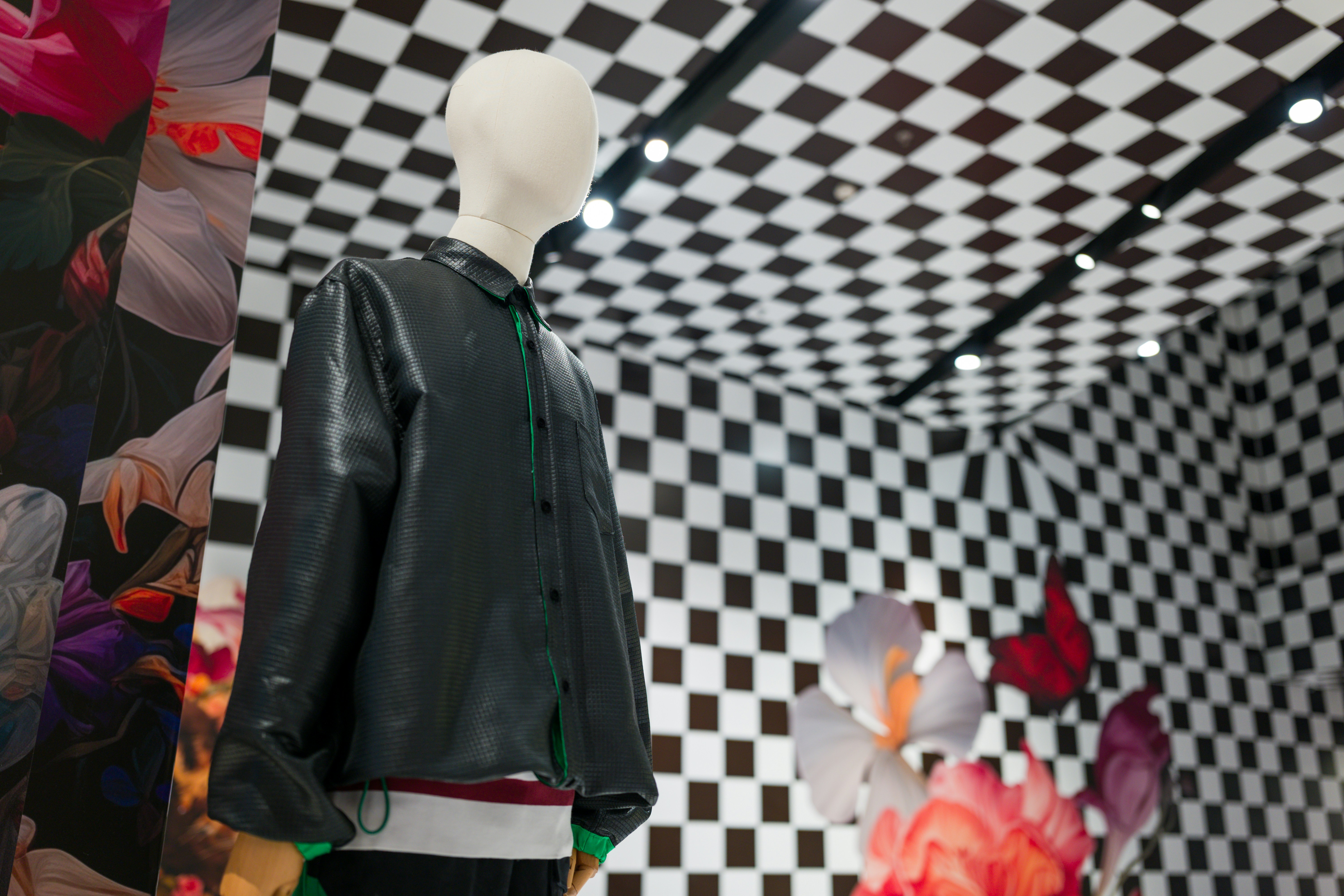 A black and white checkered wall with a mannequin