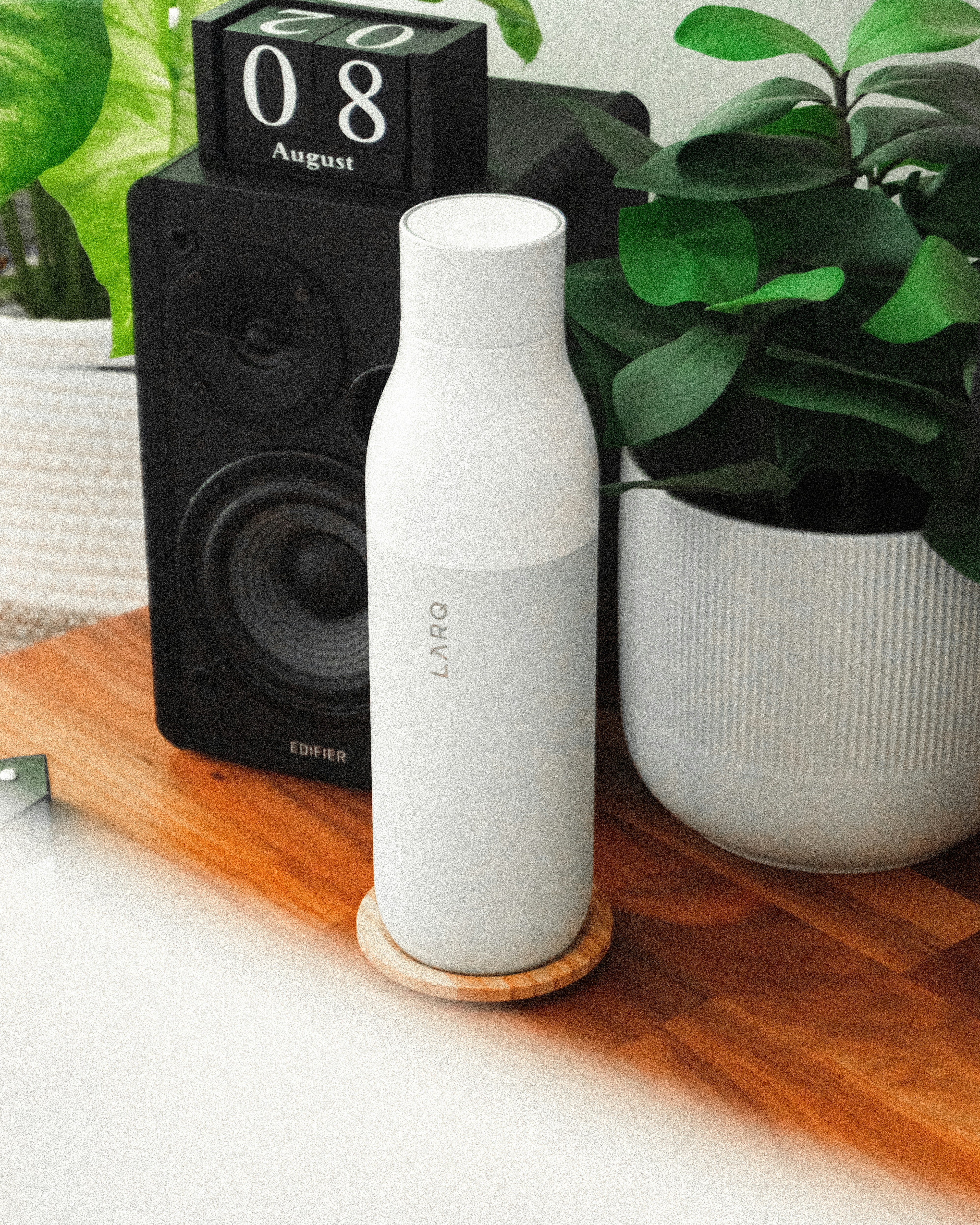 A wooden table topped with a white vase filled with plants