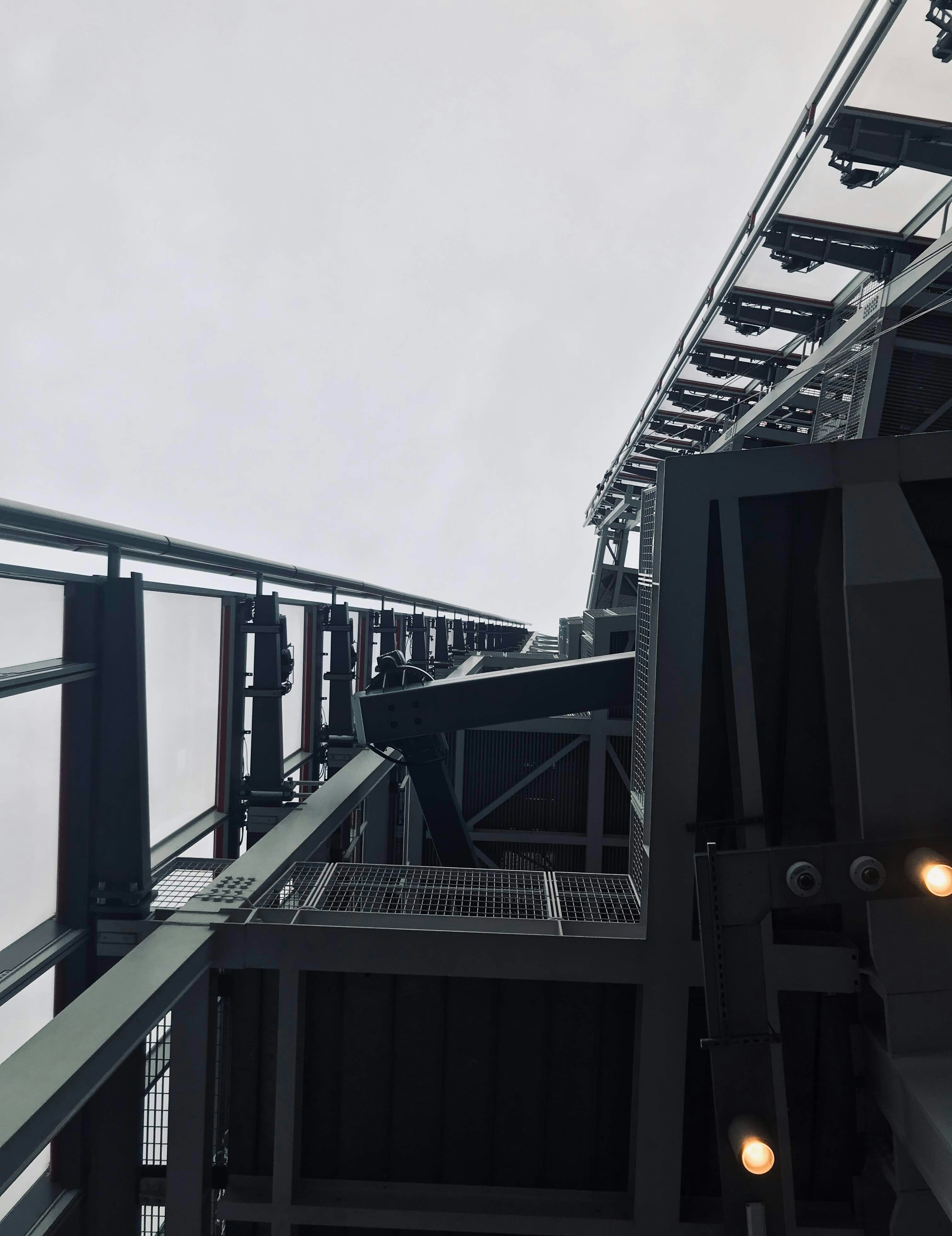Steel structural beams in industrial setting, dark overcast sky, low-key lighting, deep shadows on metal surfaces