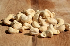 A pile of cashews sitting on top of a wooden table