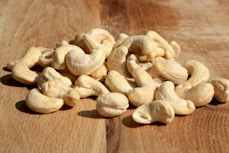 A pile of cashews sitting on top of a wooden table
