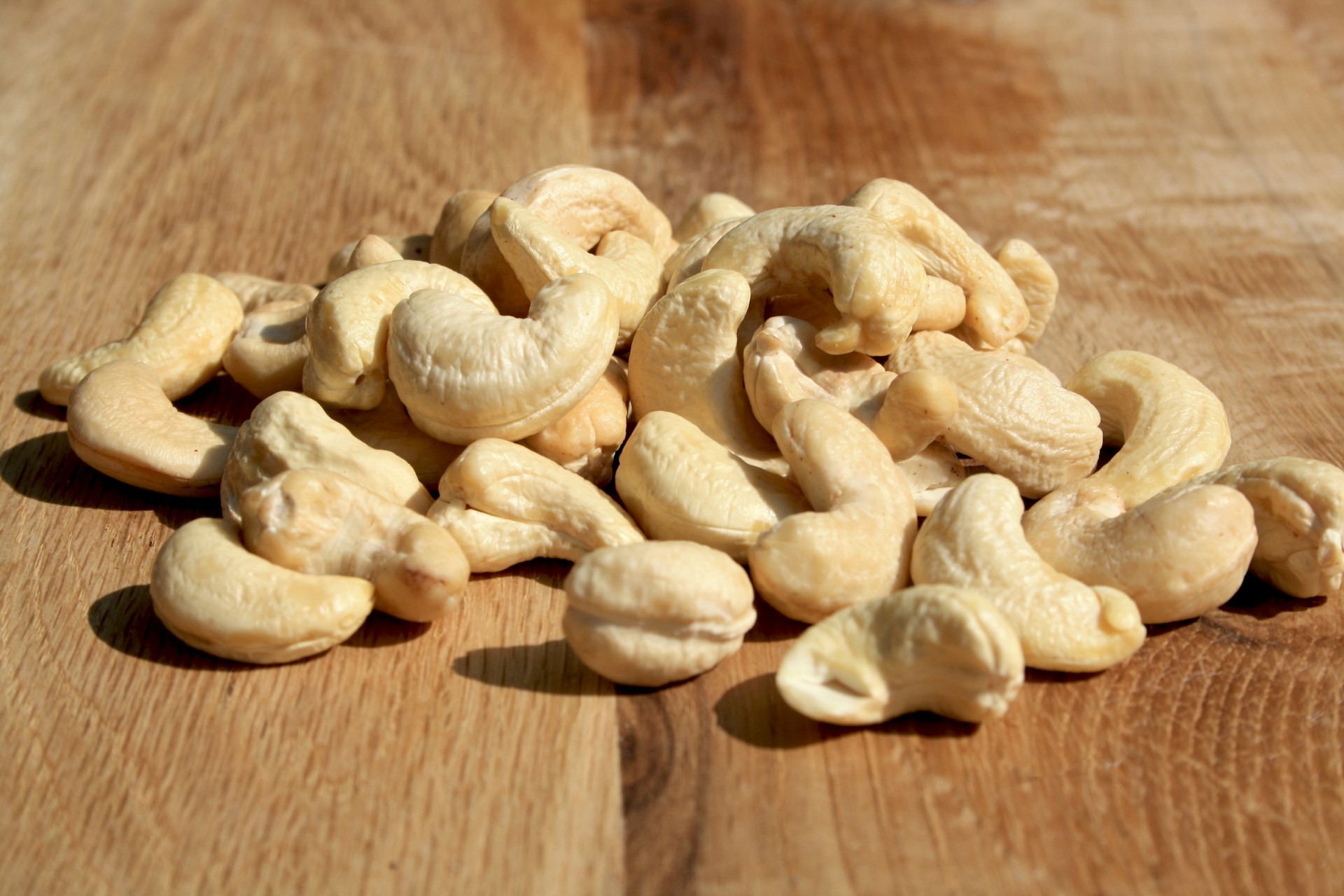 A pile of cashews sitting on top of a wooden table