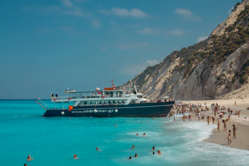 A beach with people and a boat in the water