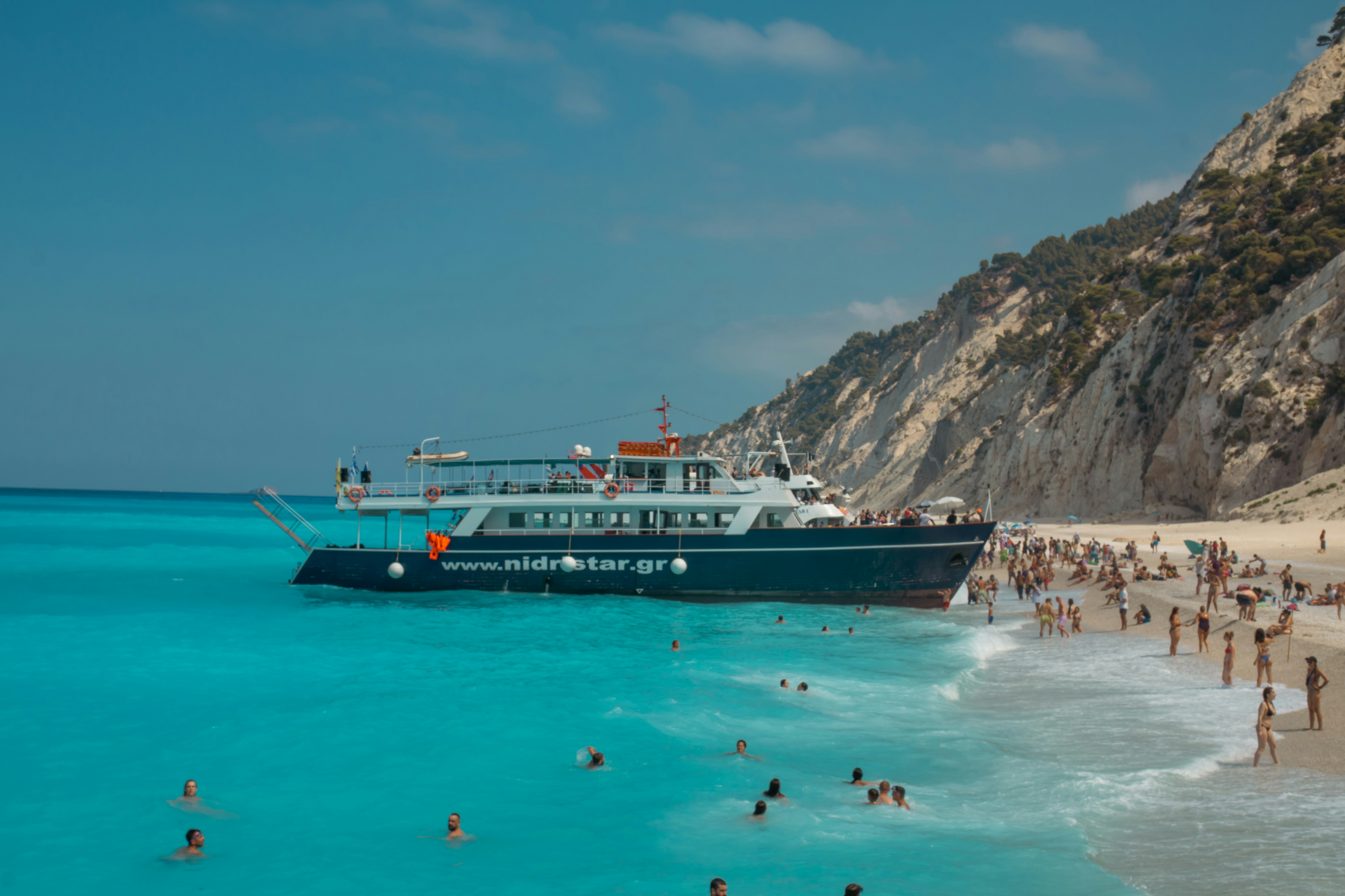 A beach with people and a boat in the water