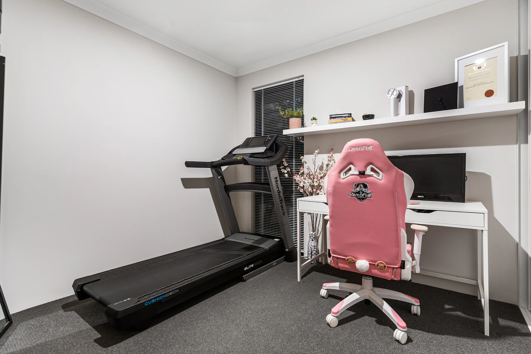 Treadmill and desk arranged in a modern home exercise room