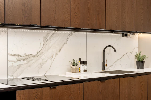 White marble slab backsplash above walnut kitchen cabinets