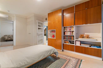 A bed sitting in a bedroom next to a book shelf