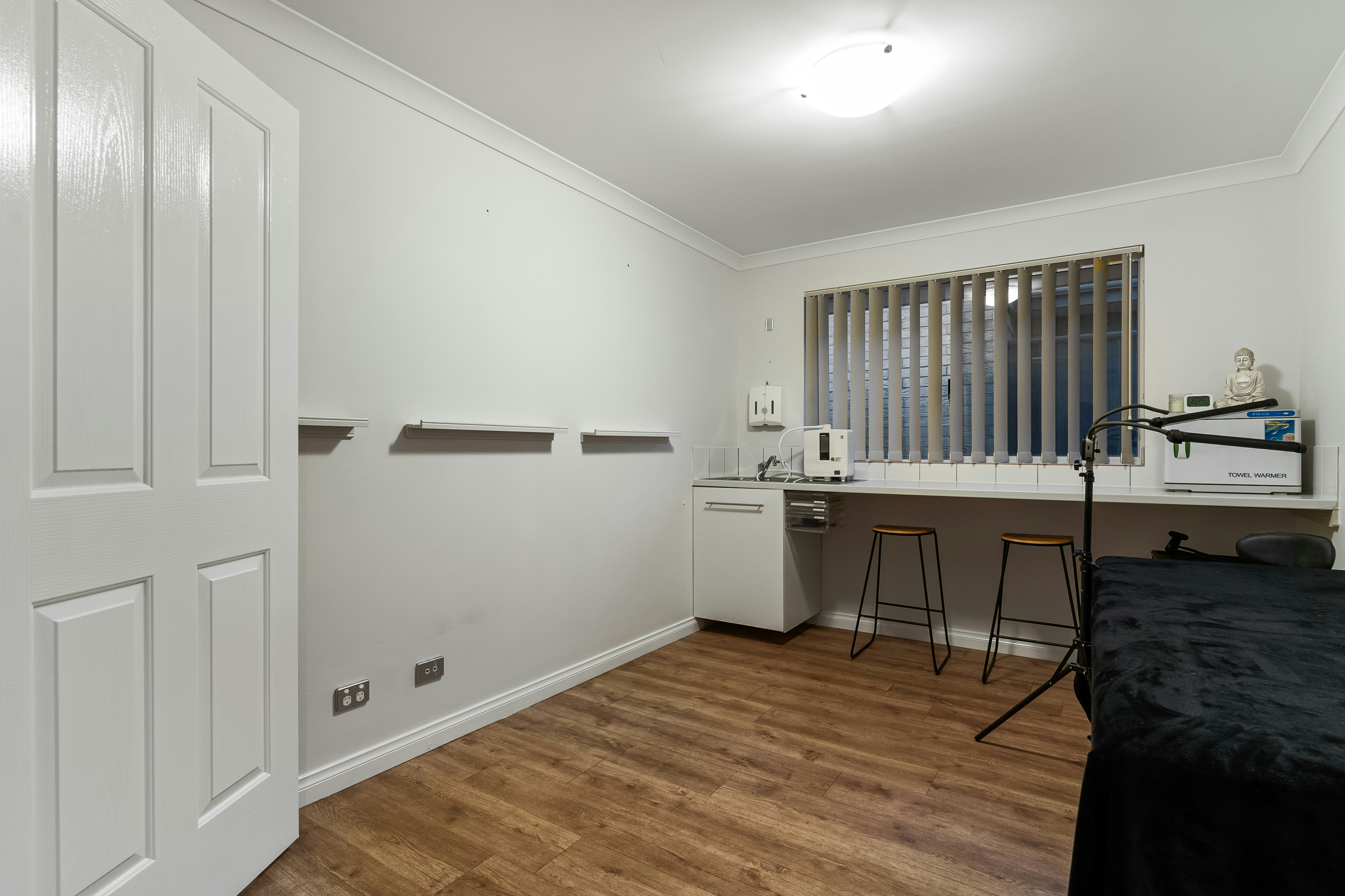 Standard wellness room with white linen, dark green accent wall, warm brass lamp