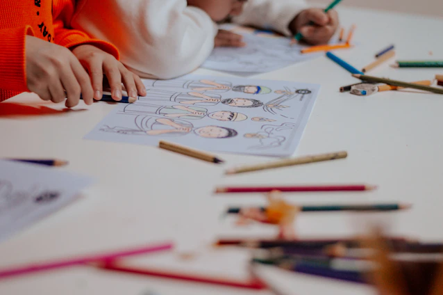 A young child sitting at a table with crayons and pencils