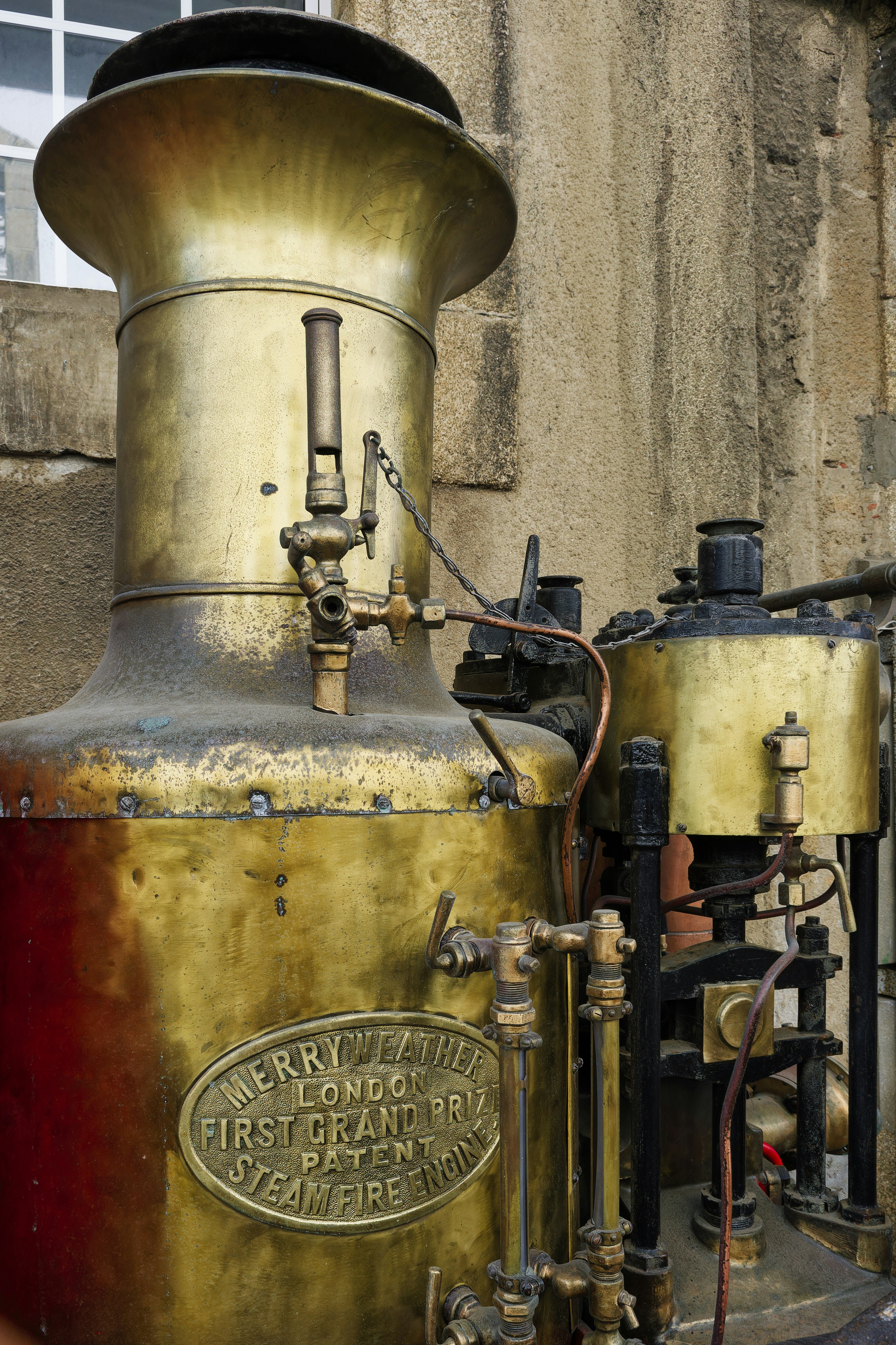 A close up of a steam engine near a building