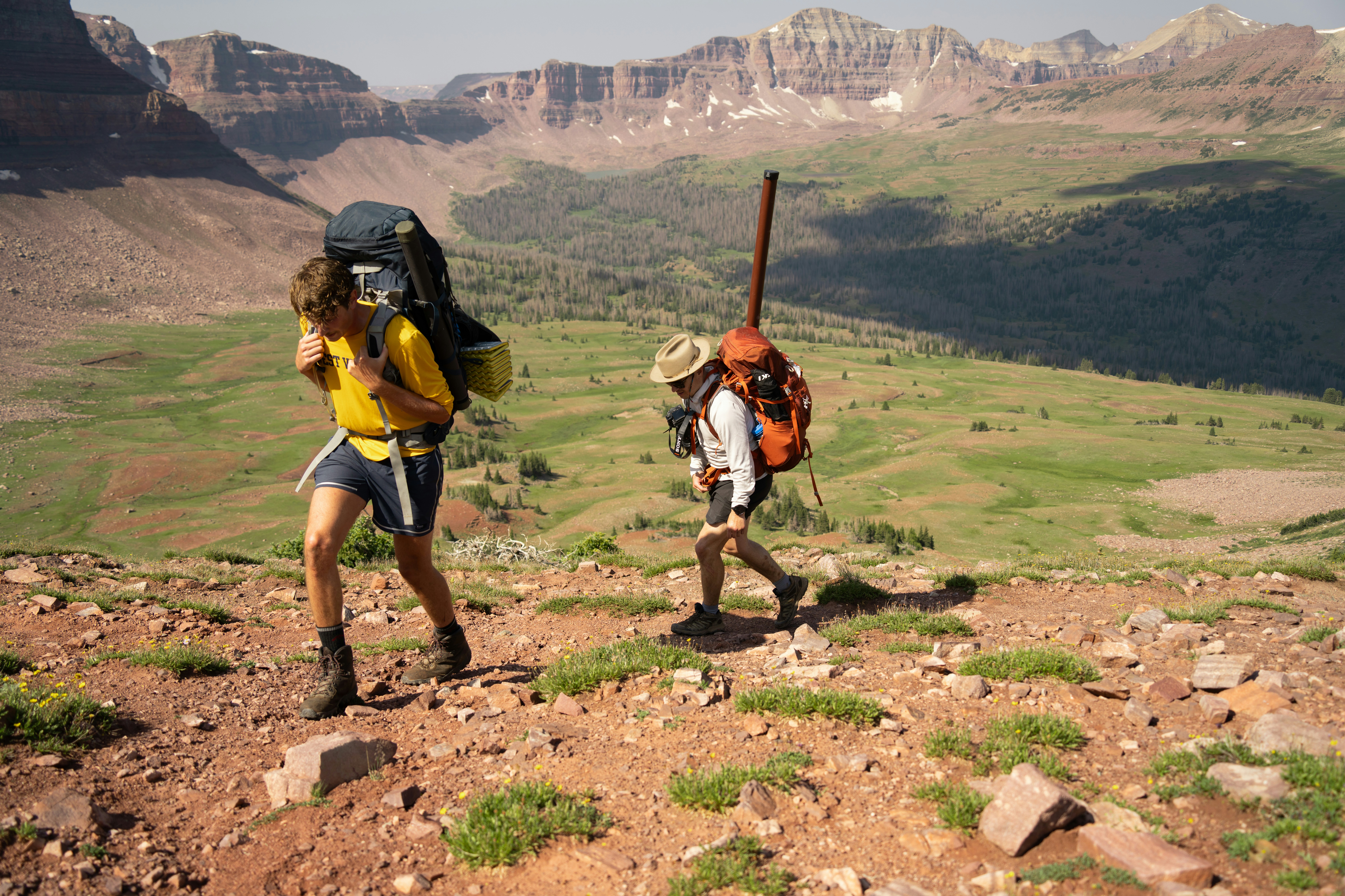 A couple of people with backpacks walking up a hill