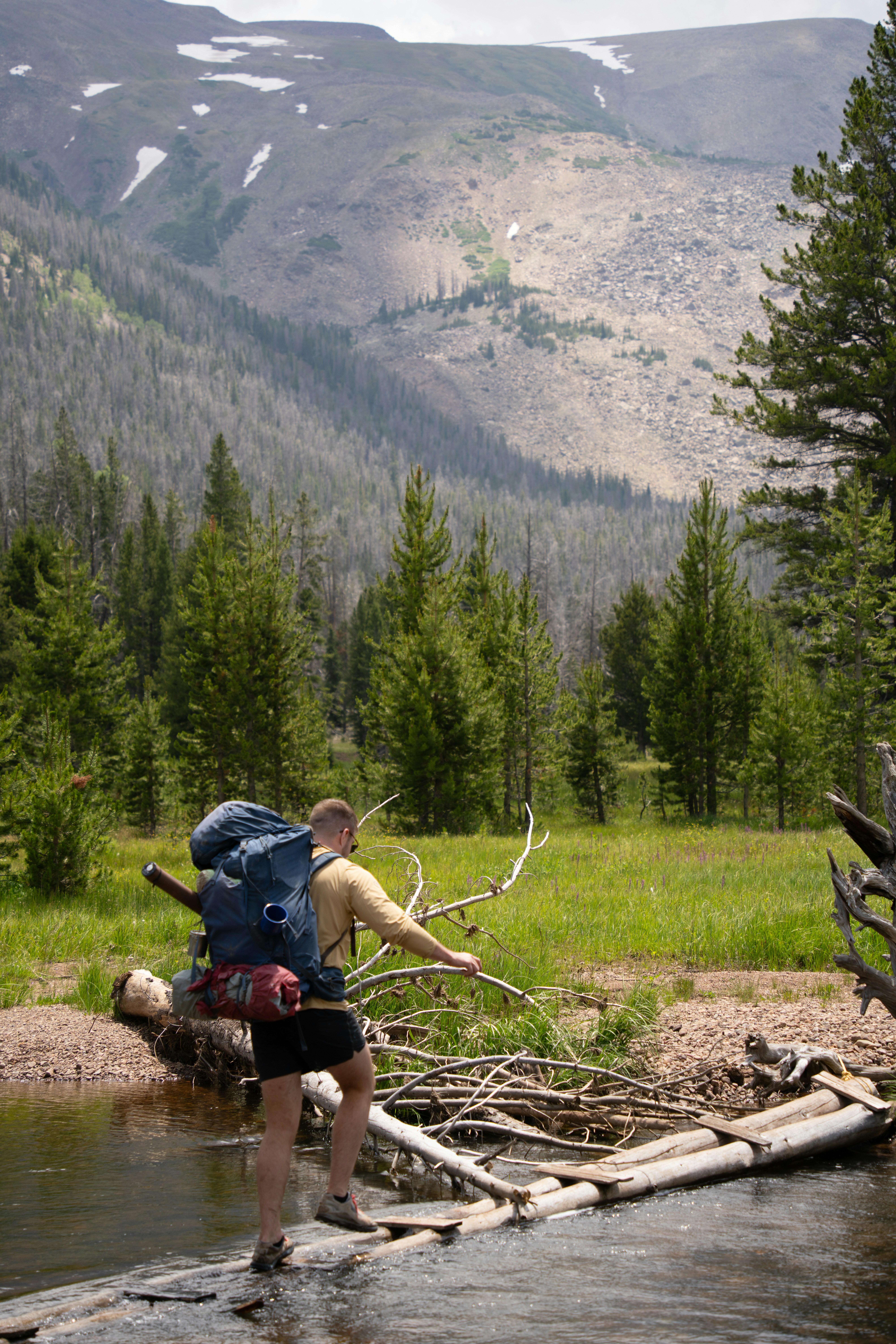 A man crossing a creek in the mountains