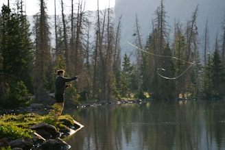 A man standing on top of a lush green field next to a lake