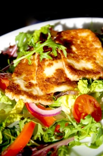 A white plate topped with a salad and meat