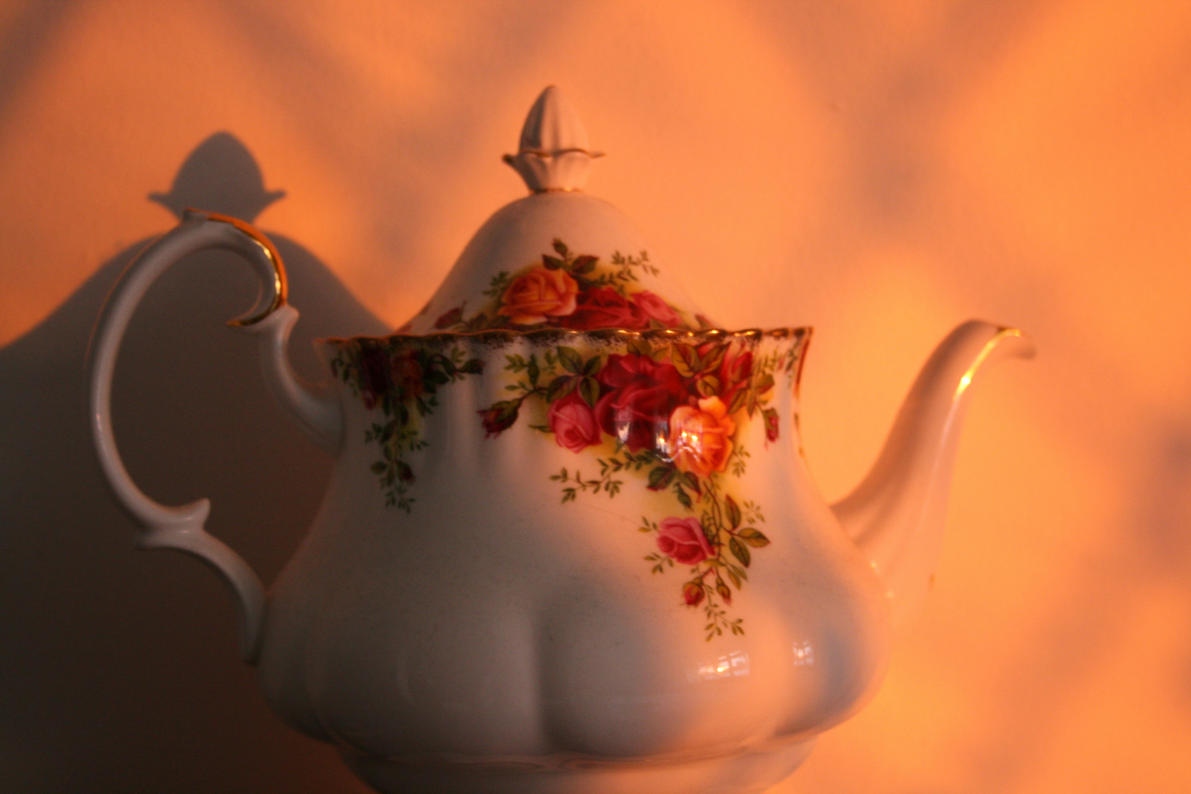 A white tea pot with a floral design on it