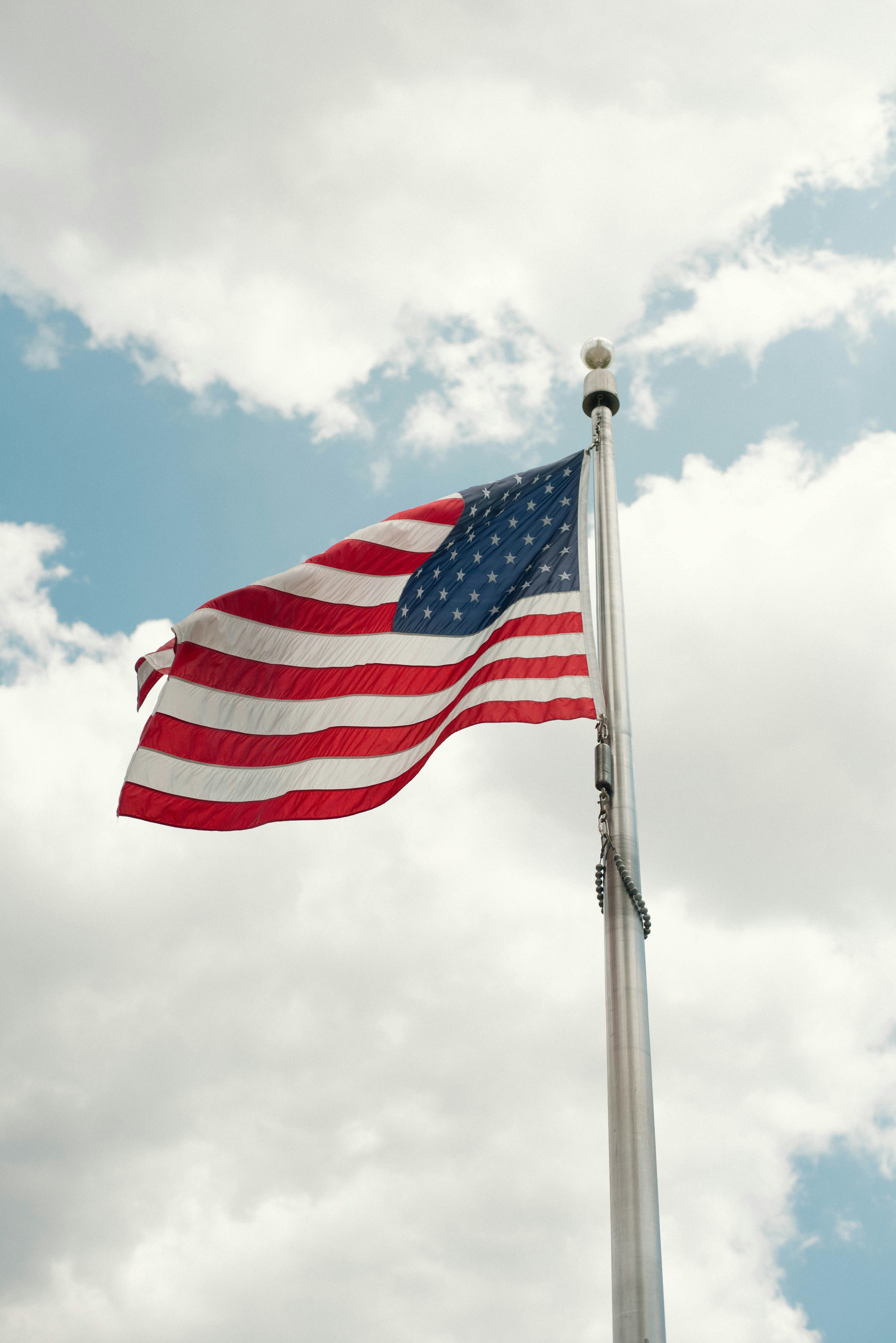 An american flag flying in the wind on a cloudy day