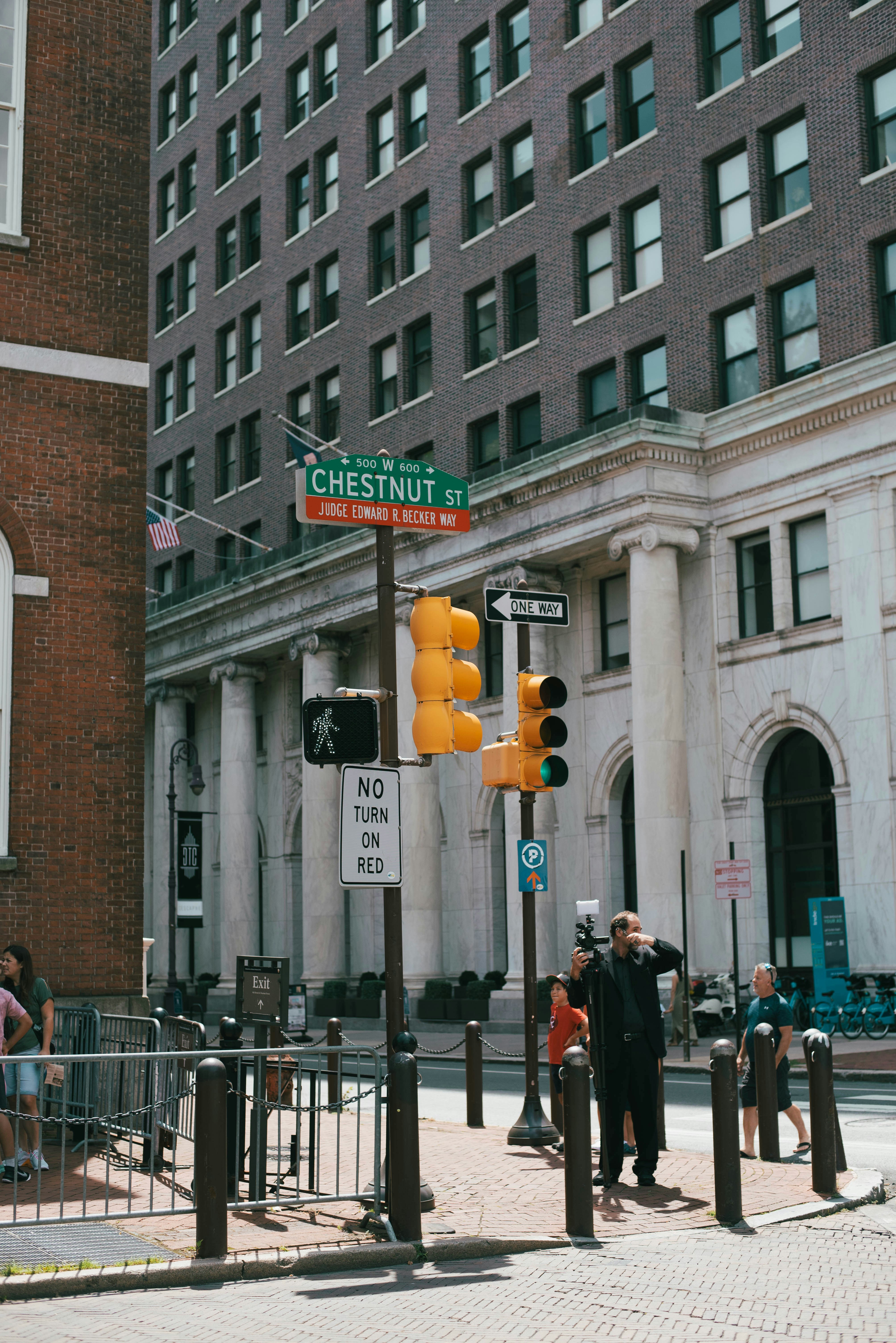 A group of people standing on a sidewalk next to a traffic light
