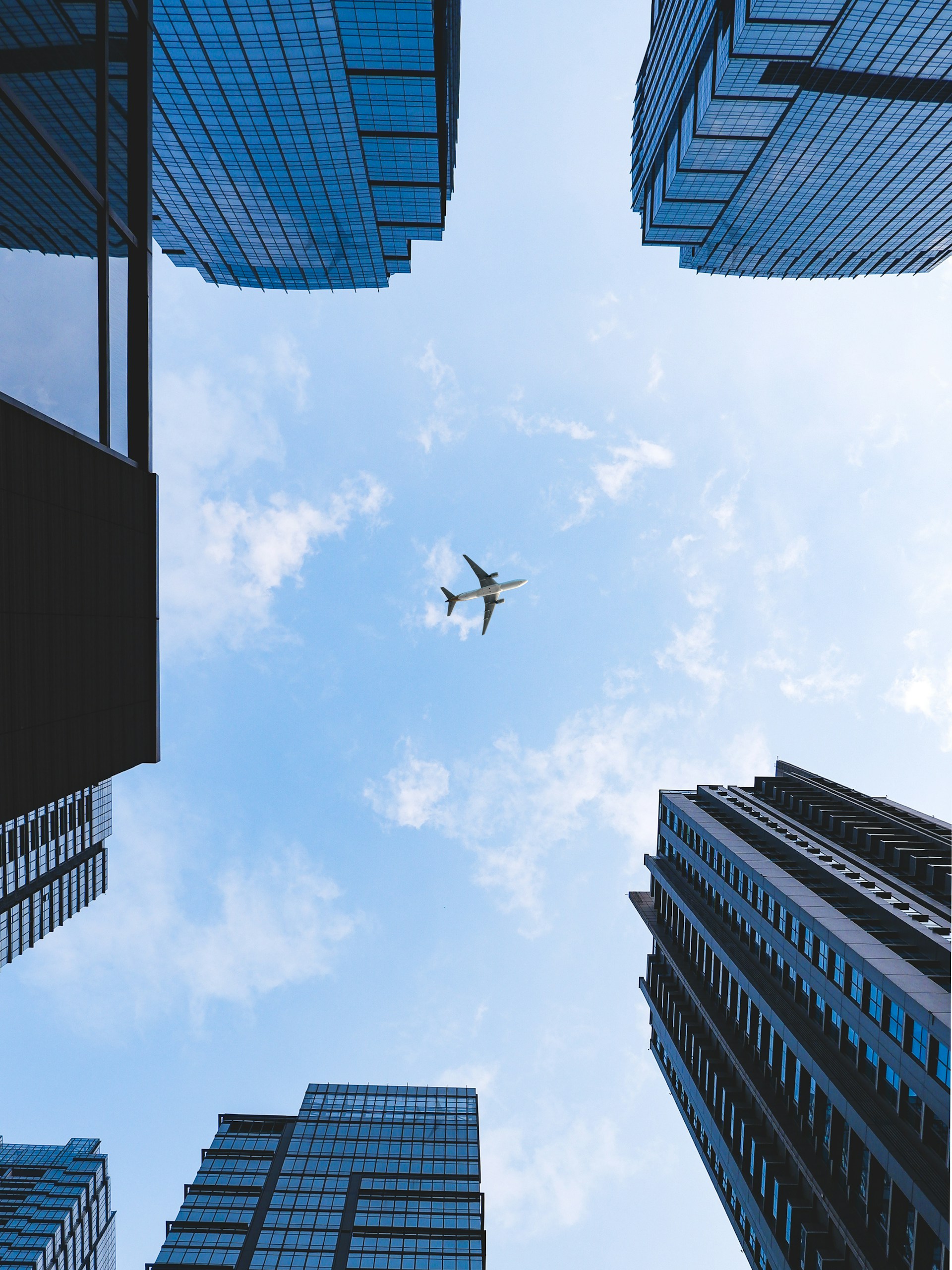 An airplane flying in the sky between tall buildings