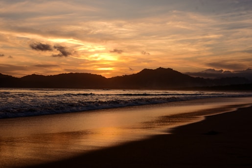 The sun is setting over the ocean on the beach