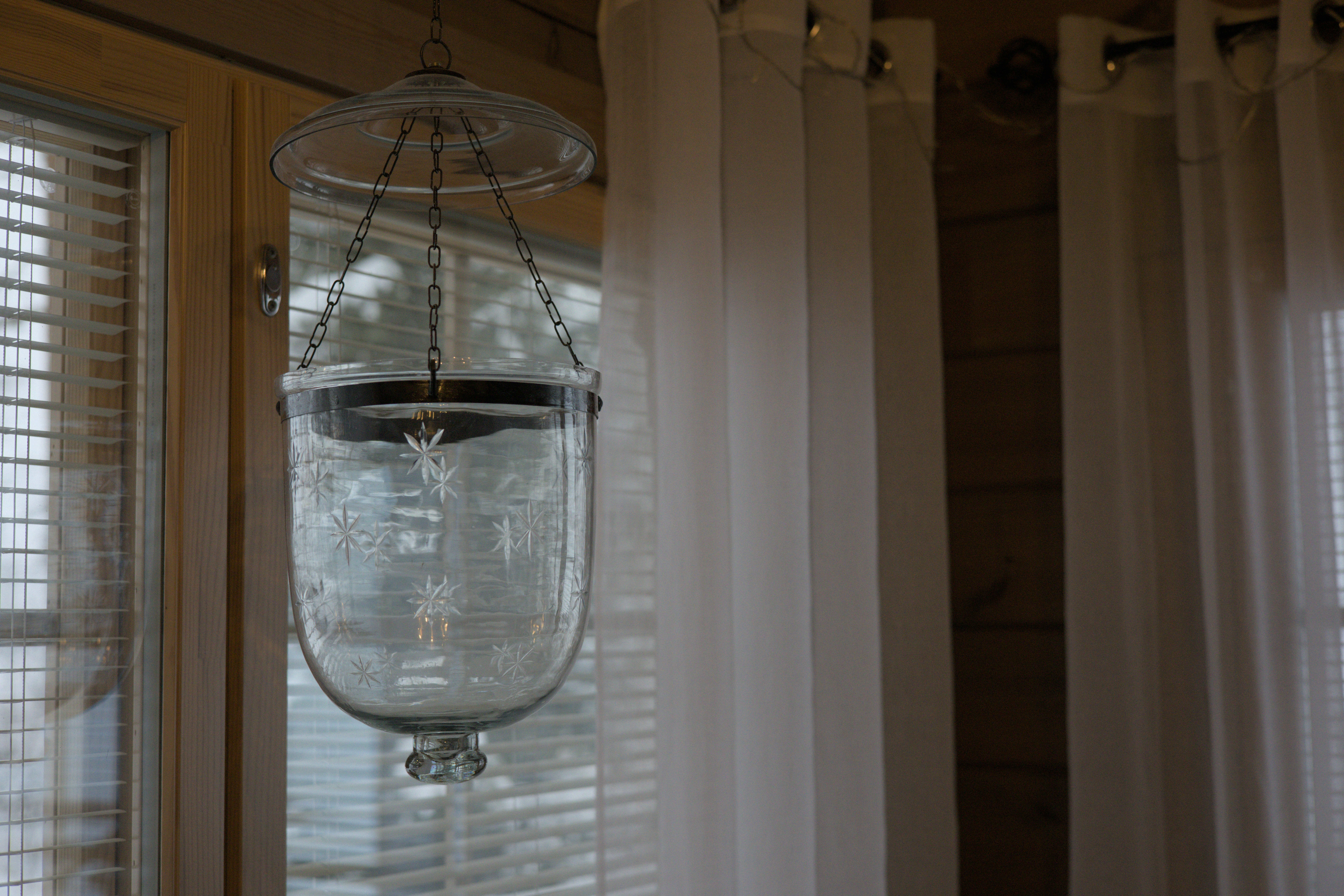 Uma lanterna de vidro pendurada em um teto ao lado de uma janela