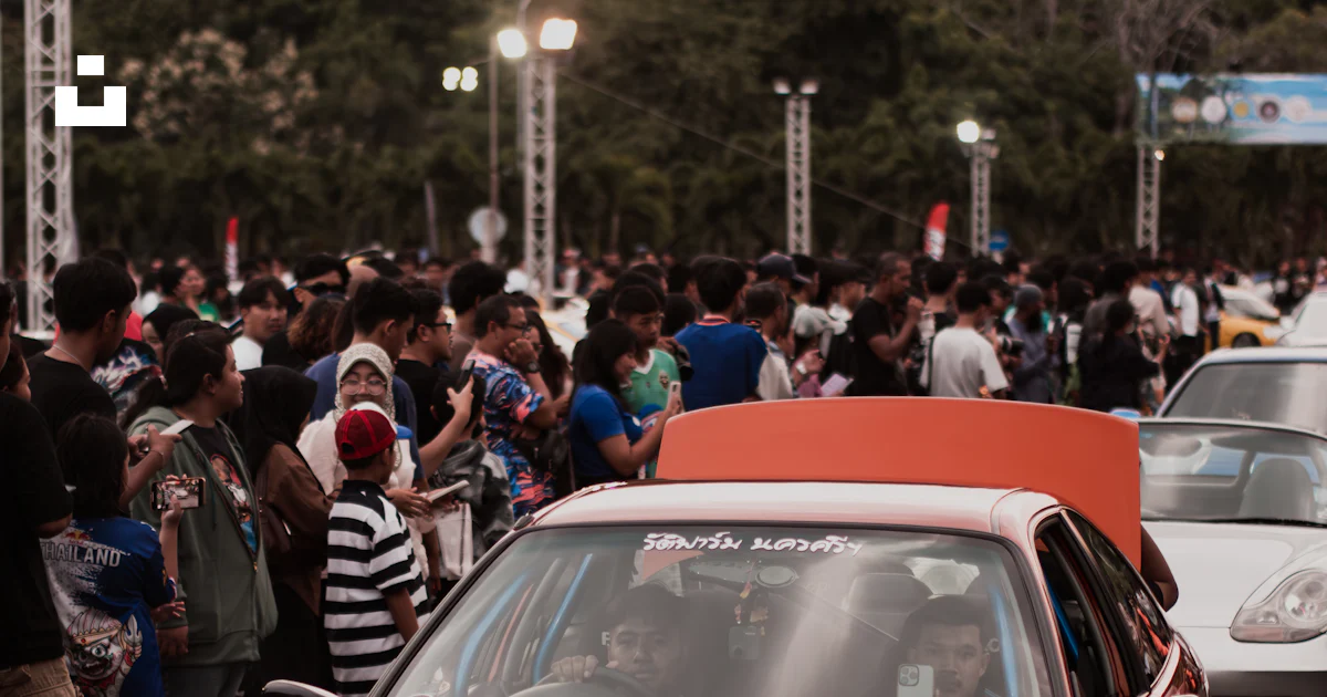 Auto Crowed A group of cars driving down a street next to a crowd of people photo ...