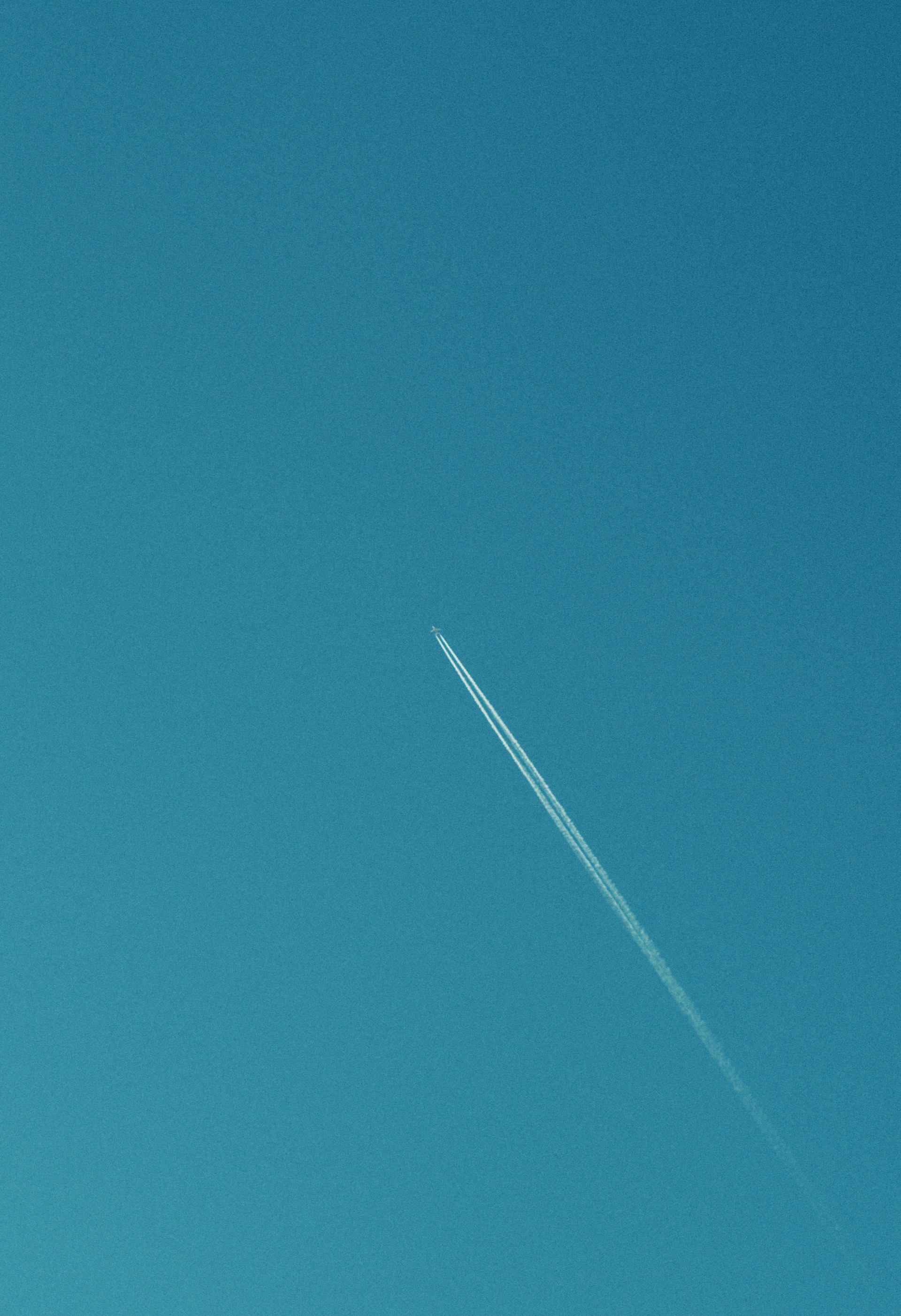 A jet flying through a blue sky with a contrail