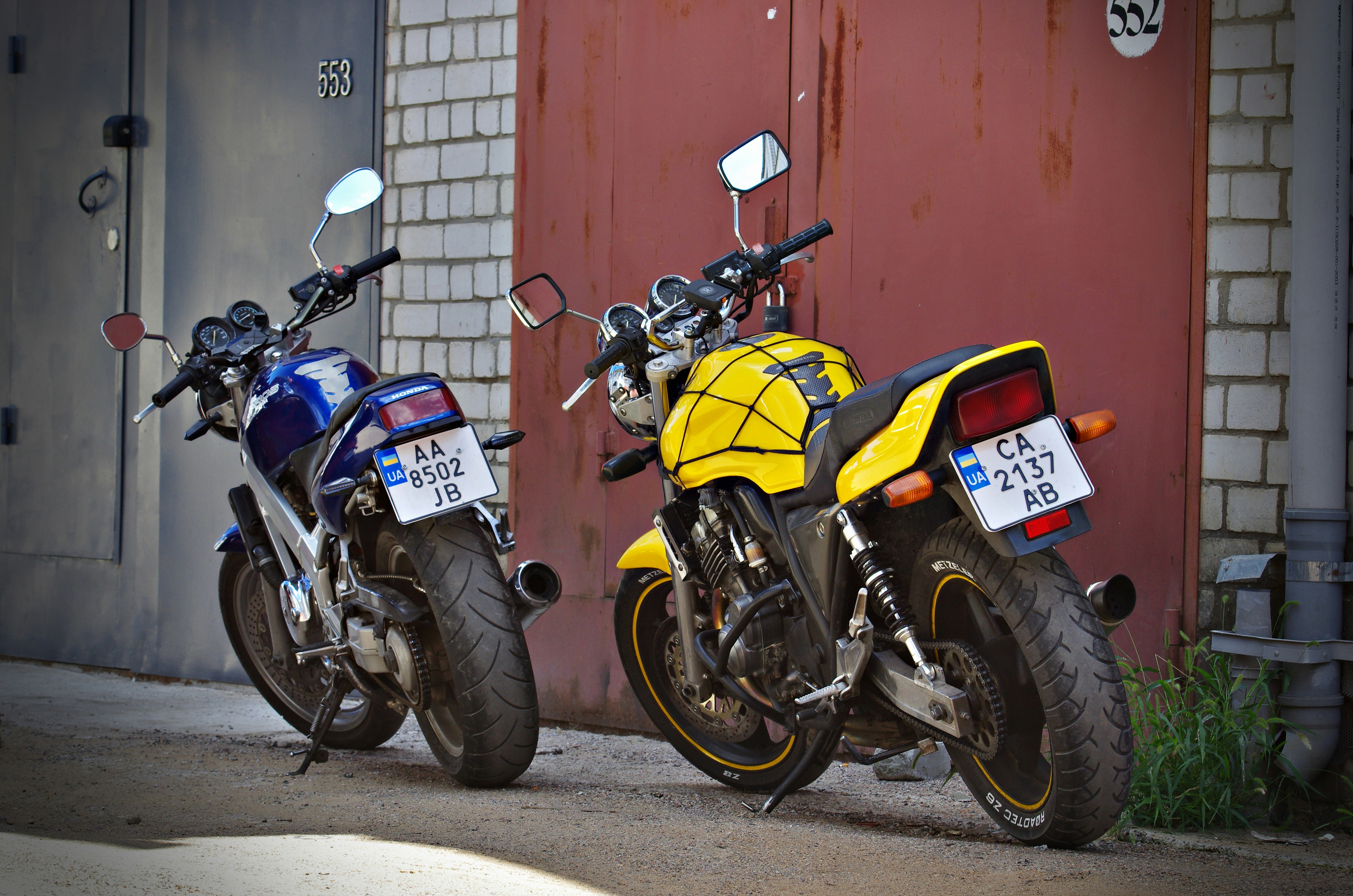 Two motorcycles parked next to each other in front of a building