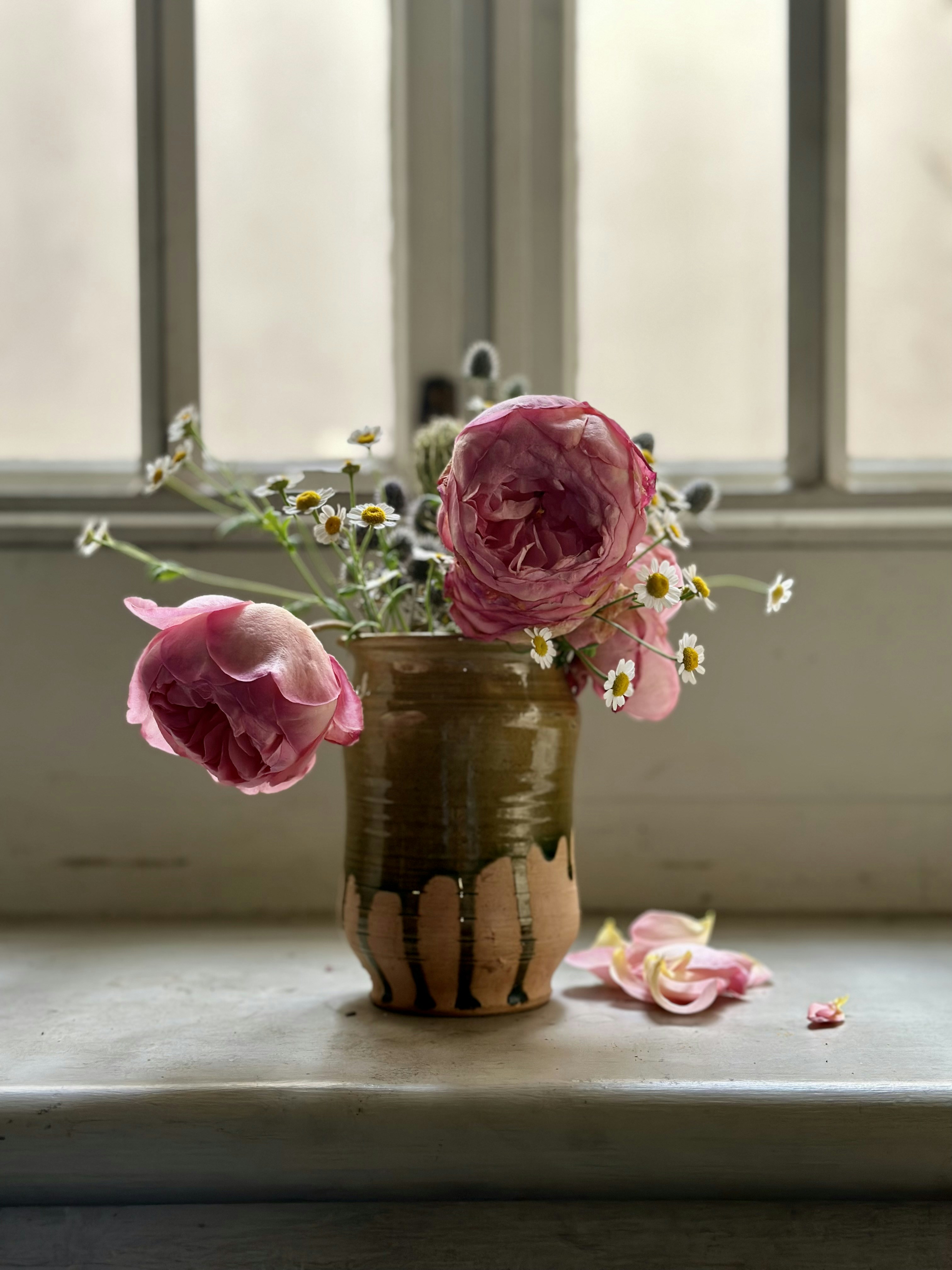 A vase filled with pink flowers sitting on a window sill