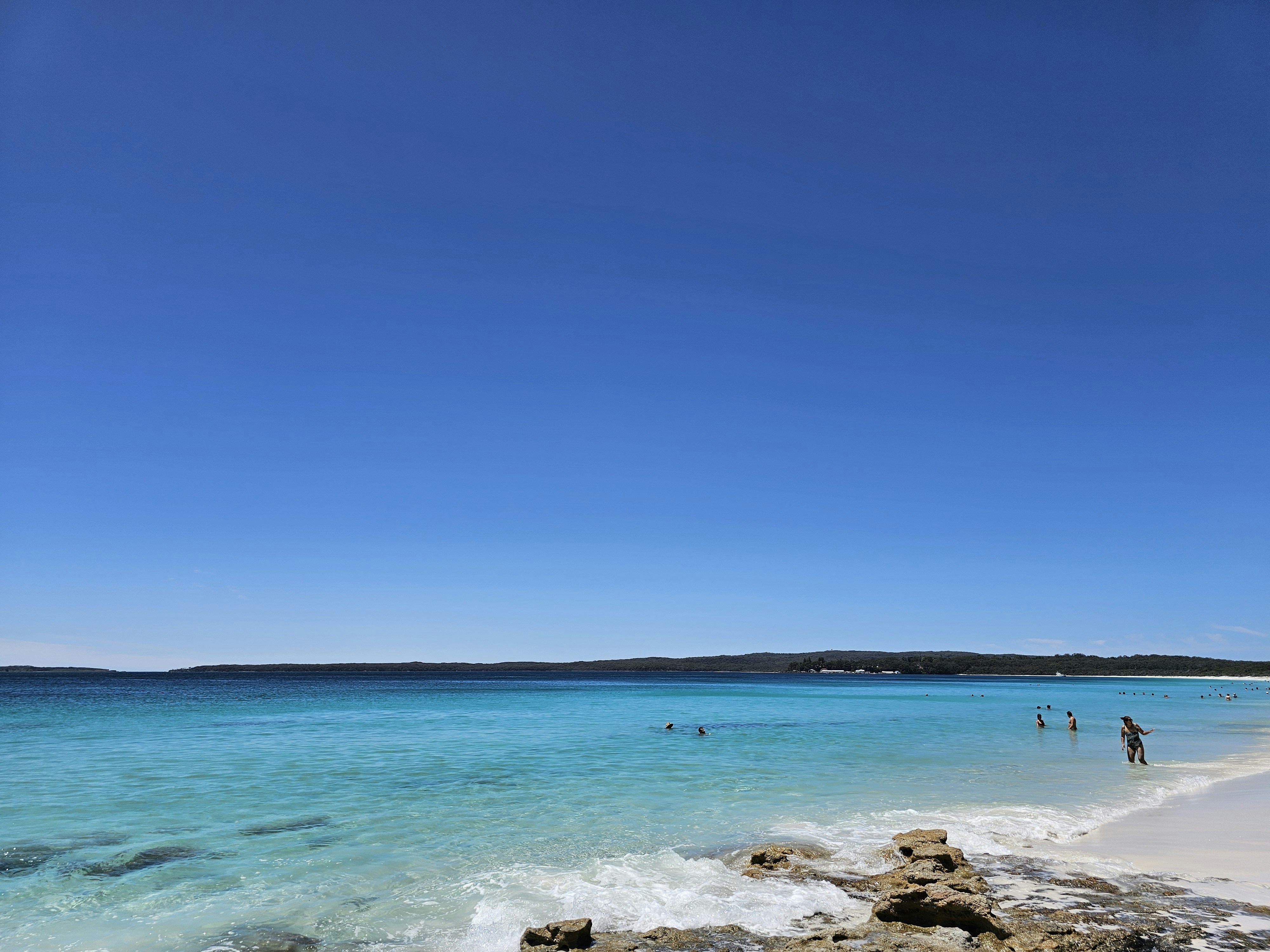 A beach with people walking on the sand and water