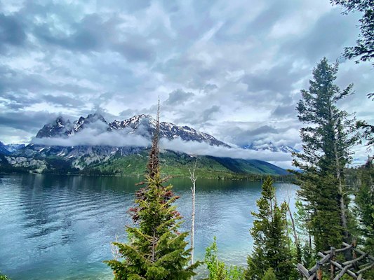 A lake surrounded by trees and mountains under a cloudy sky — Grand Teton, United States