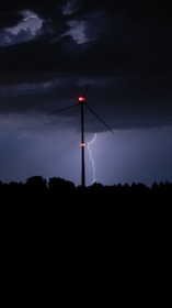 A windmill with a red light in the middle of a field