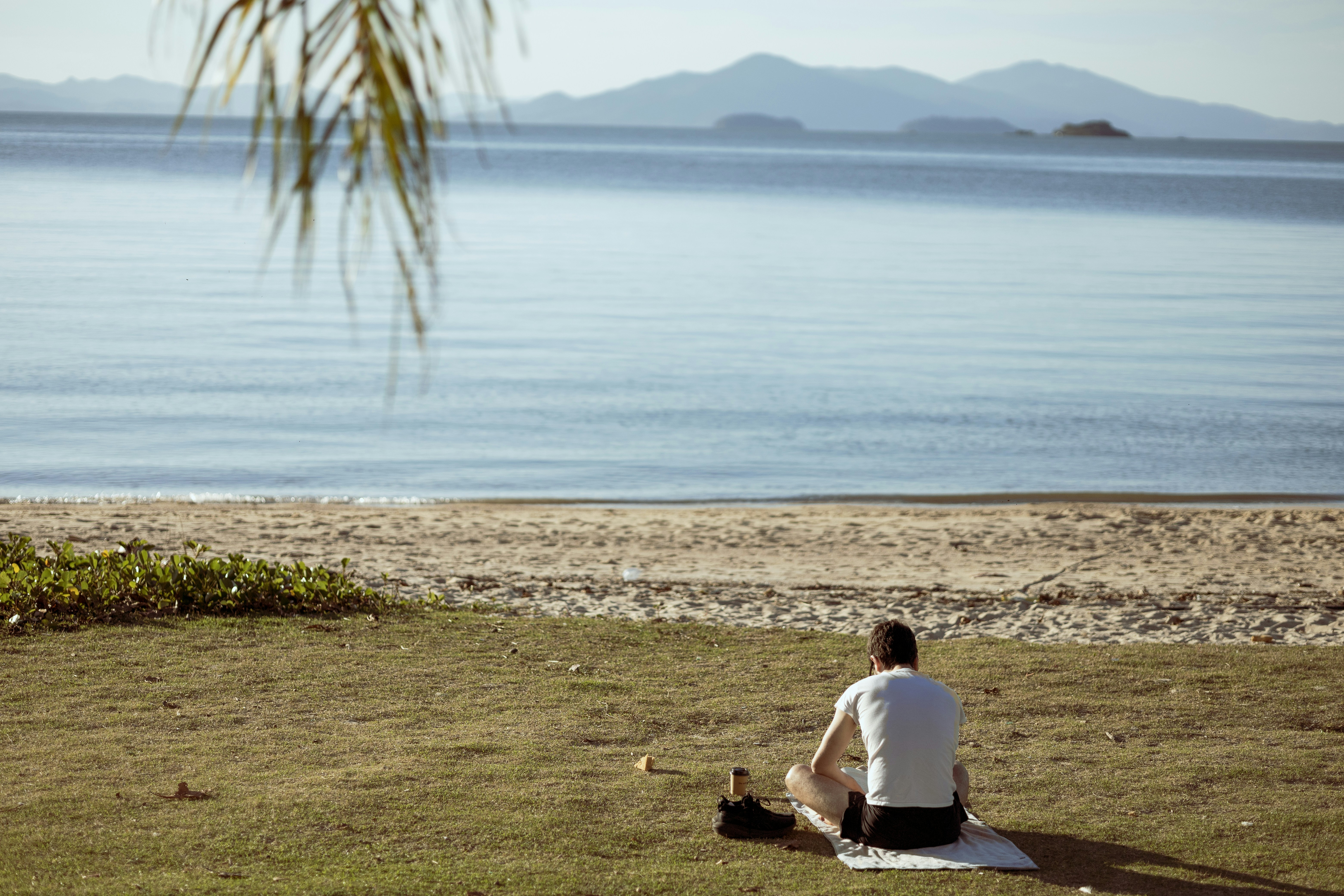 A man sitting on the grass by the water