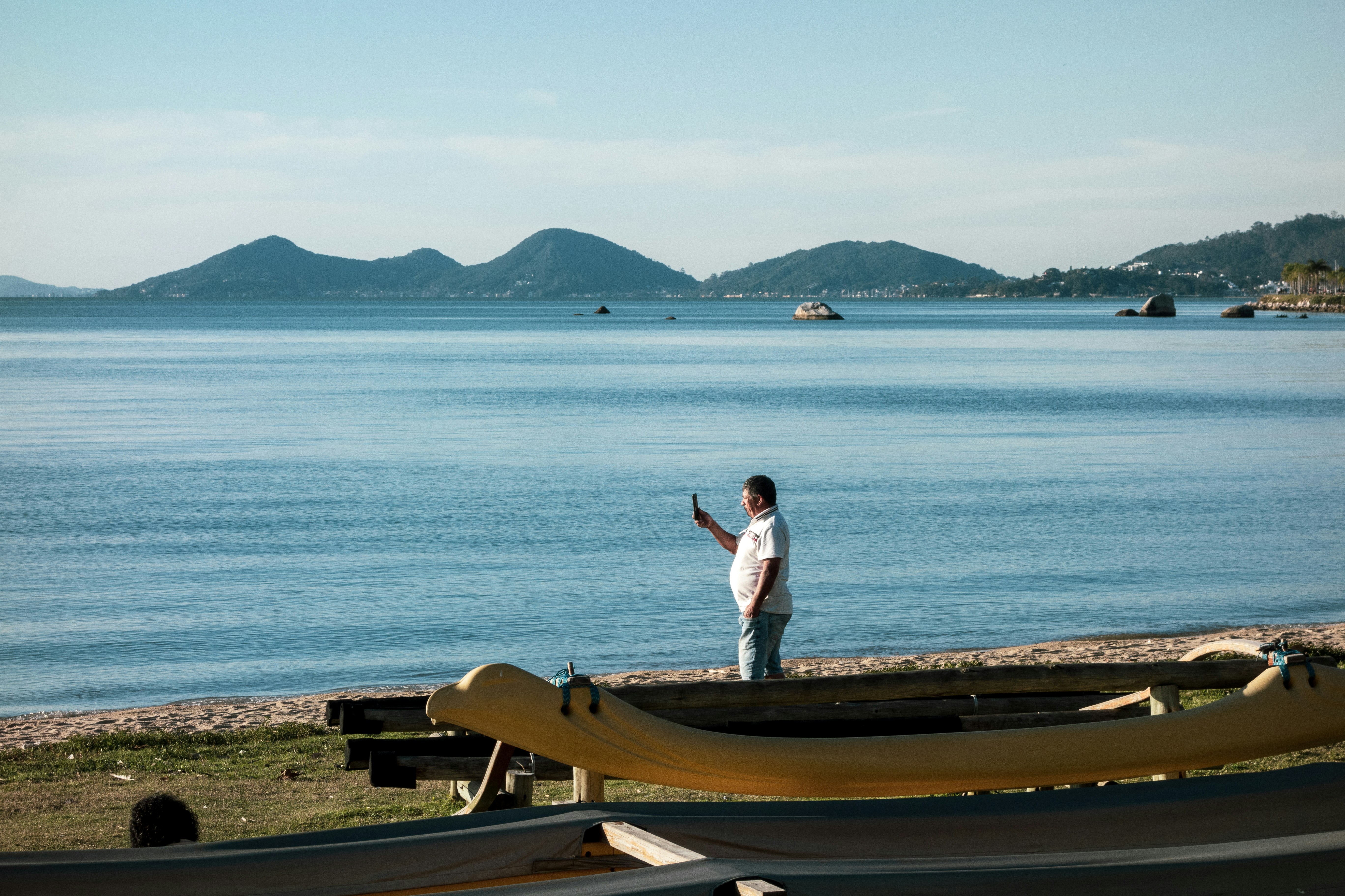 A man standing on a beach next to a boat