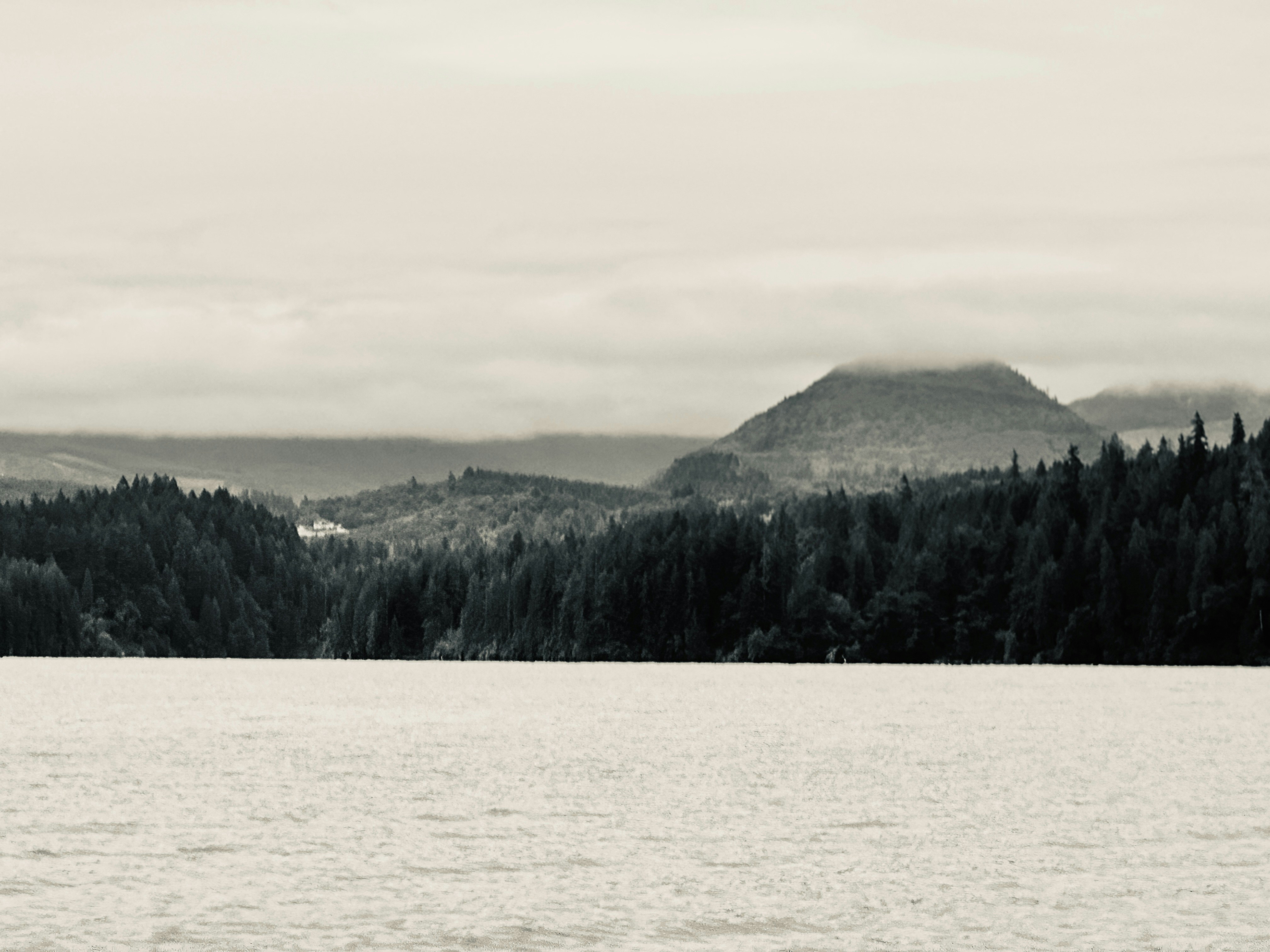A black and white photo of a lake with mountains in the background