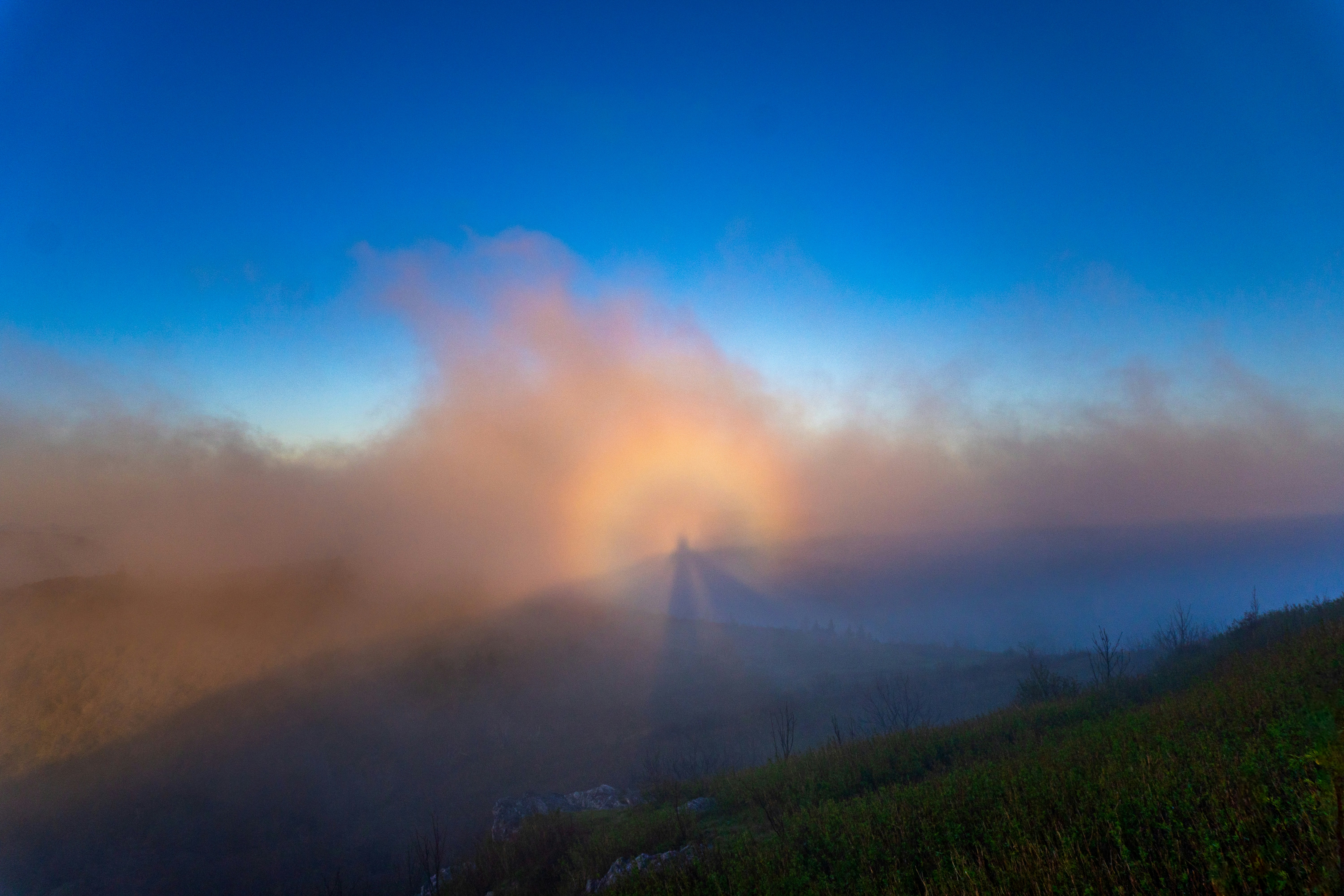 A foggy mountain with a rainbow in the sky