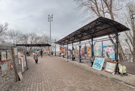 A group of people walking down a sidewalk next to a covered walkway