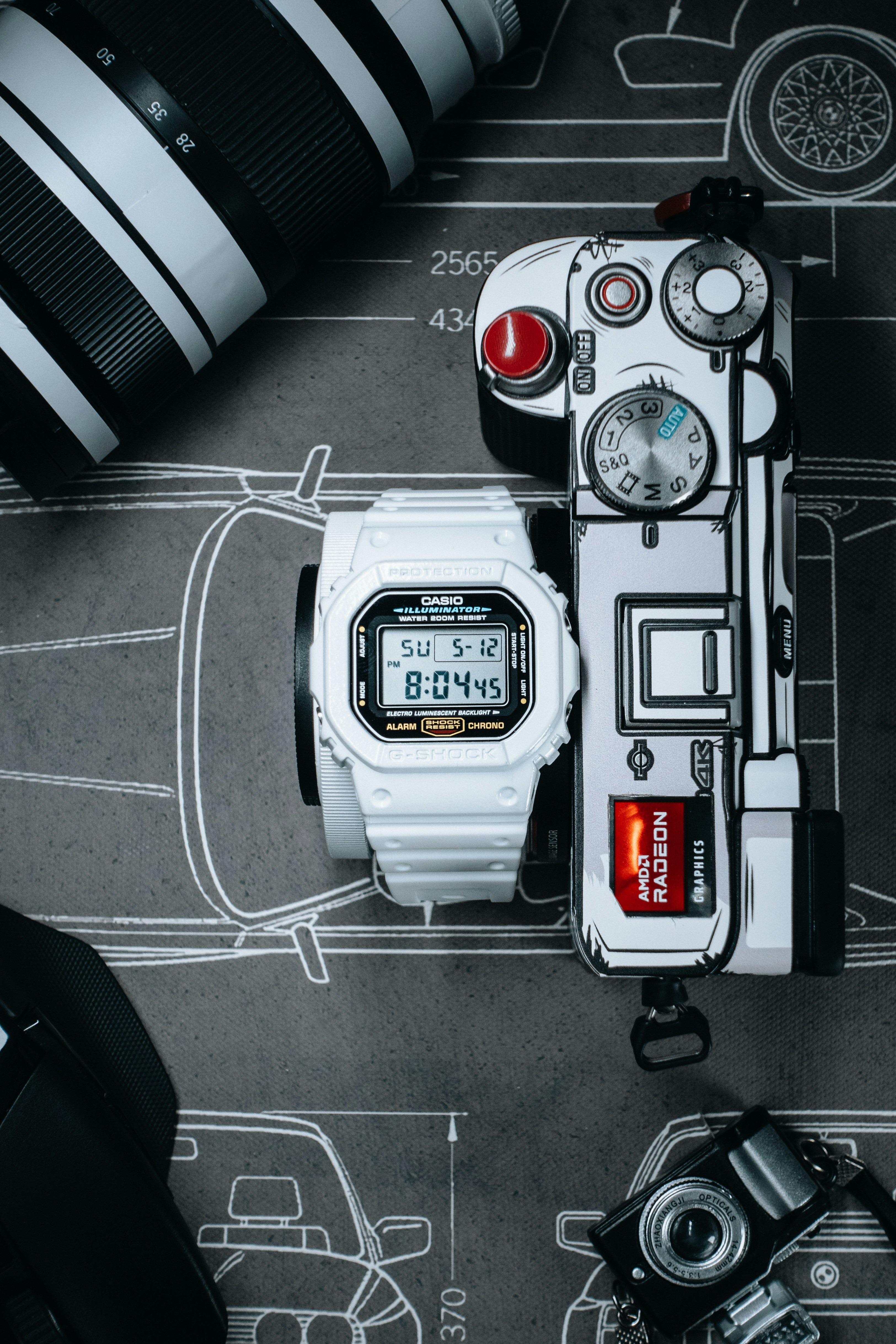 A white watch sitting on top of a table next to a camera