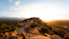 The sun is setting over a rocky hill