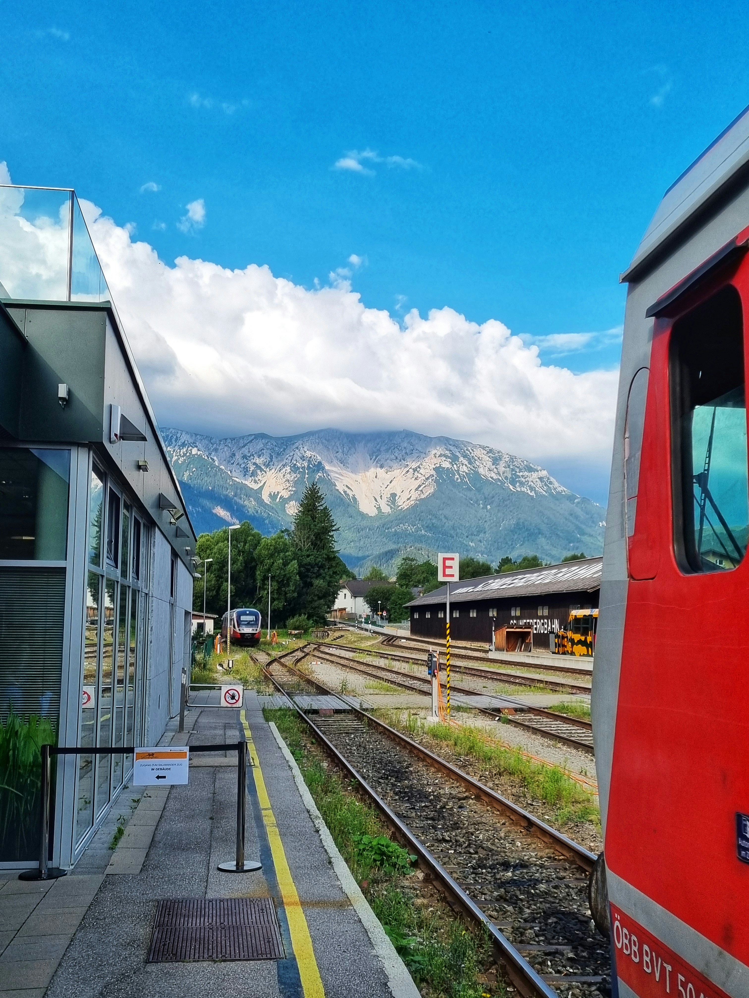 Ein roter Zug, der neben einem Bahnhof die Gleise entlangfährt
