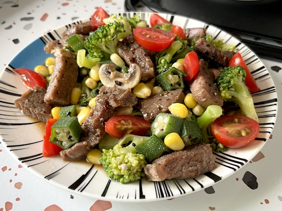 A white plate topped with meat and veggies