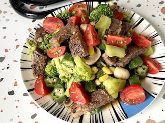 A plate of food with broccoli, tomatoes, and meat