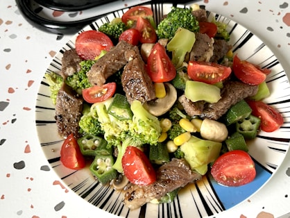 A plate of food with broccoli, tomatoes, and meat
