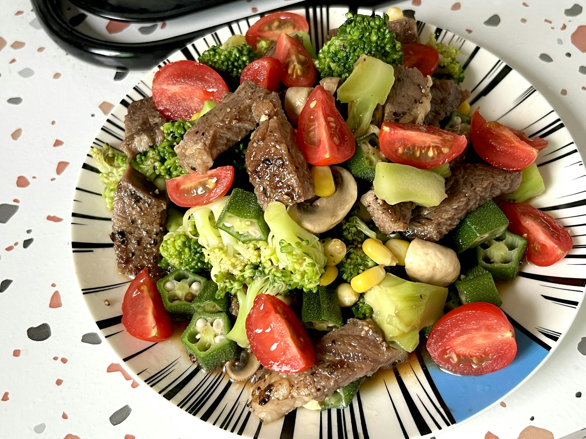 A plate of food with broccoli, tomatoes, and meat