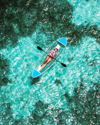 A person in a blue kayak in the middle of the ocean