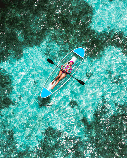 A person in a blue kayak in the middle of the ocean