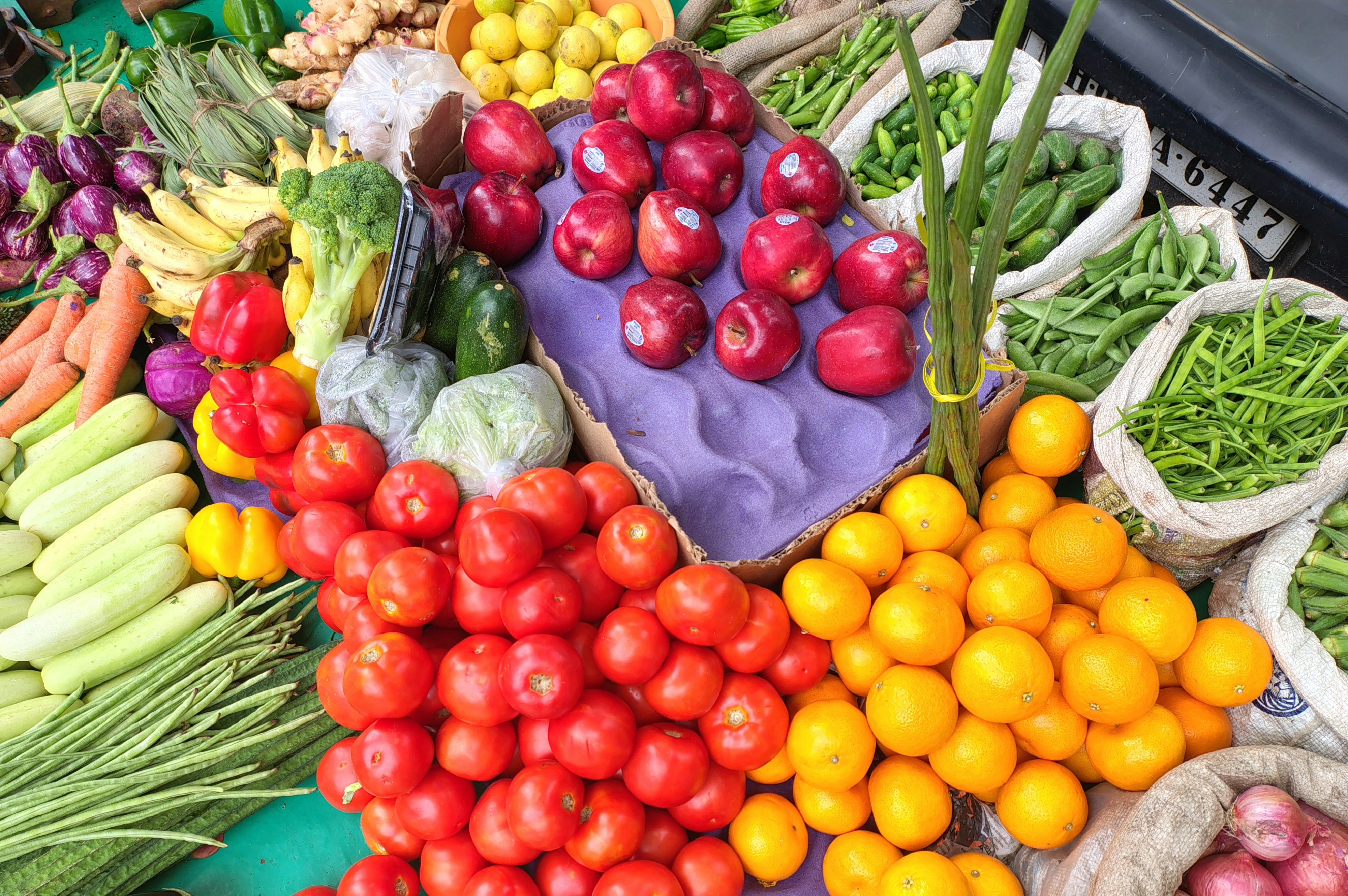 Market reyonunda taze sebze ve meyveler arasından bütçesine uygun seçim yapan bir kişinin elleri ve alışveriş sepeti.