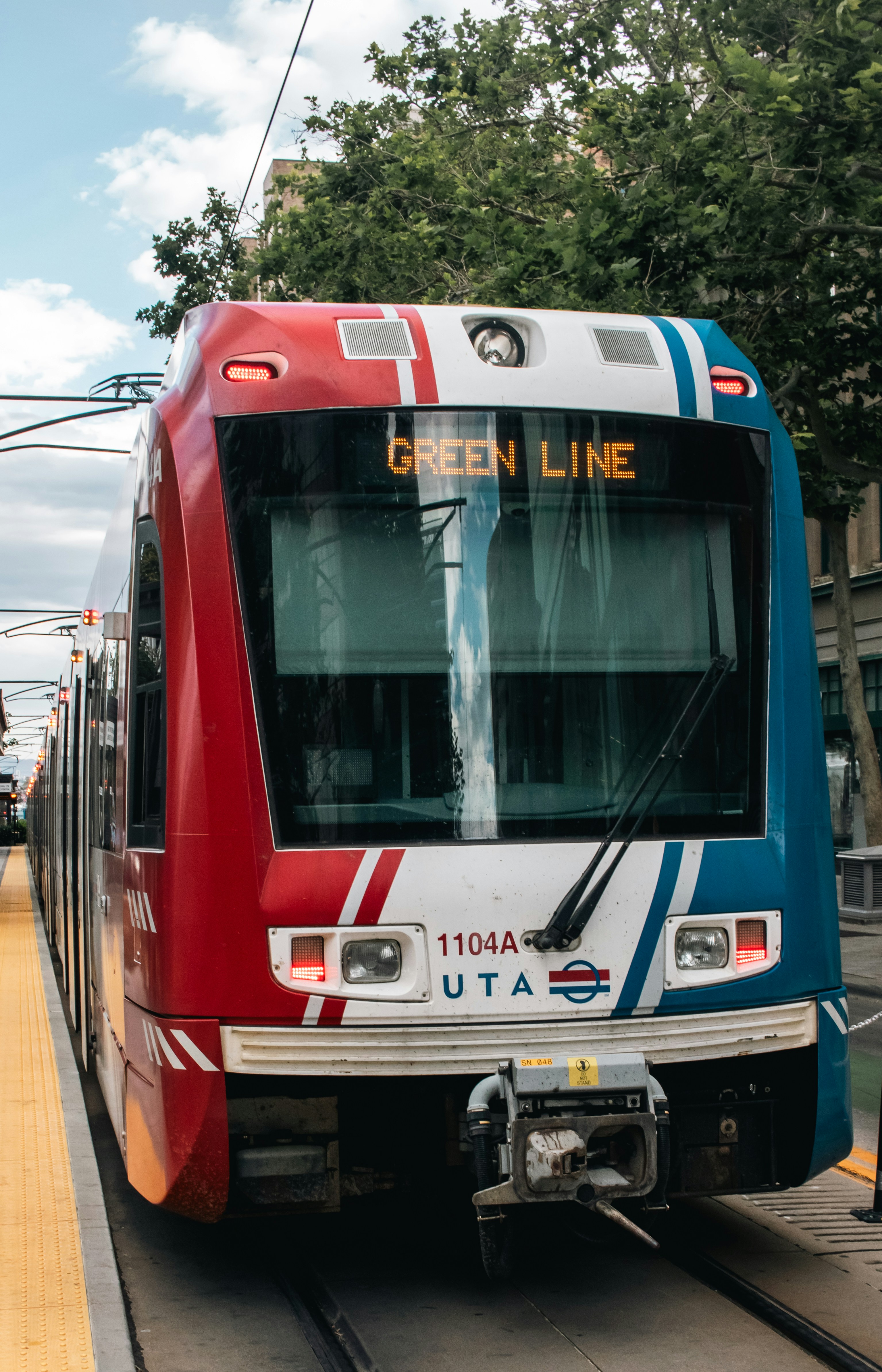 A red, white and blue train pulling into a train station
