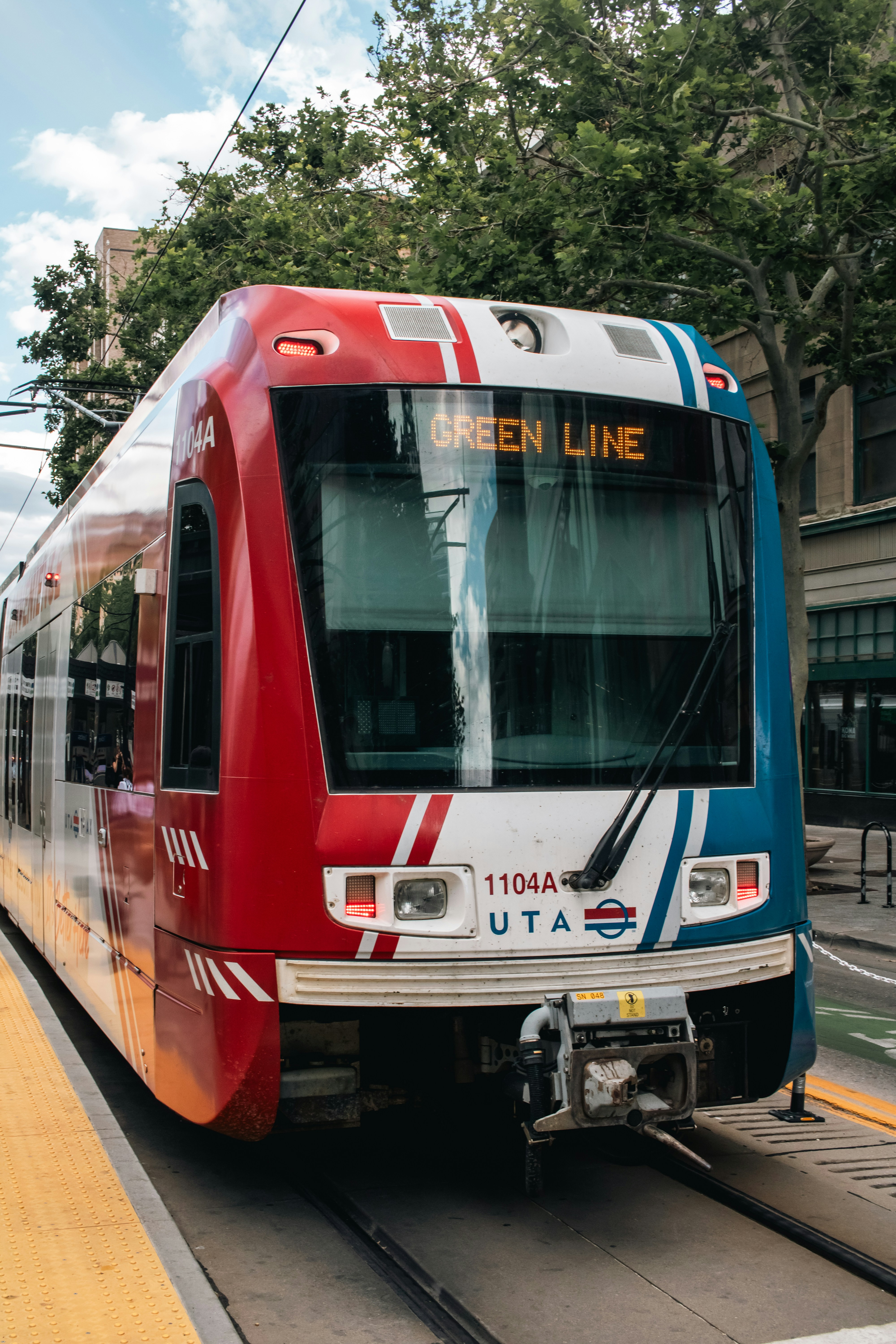 A red, white and blue train pulling into a train station