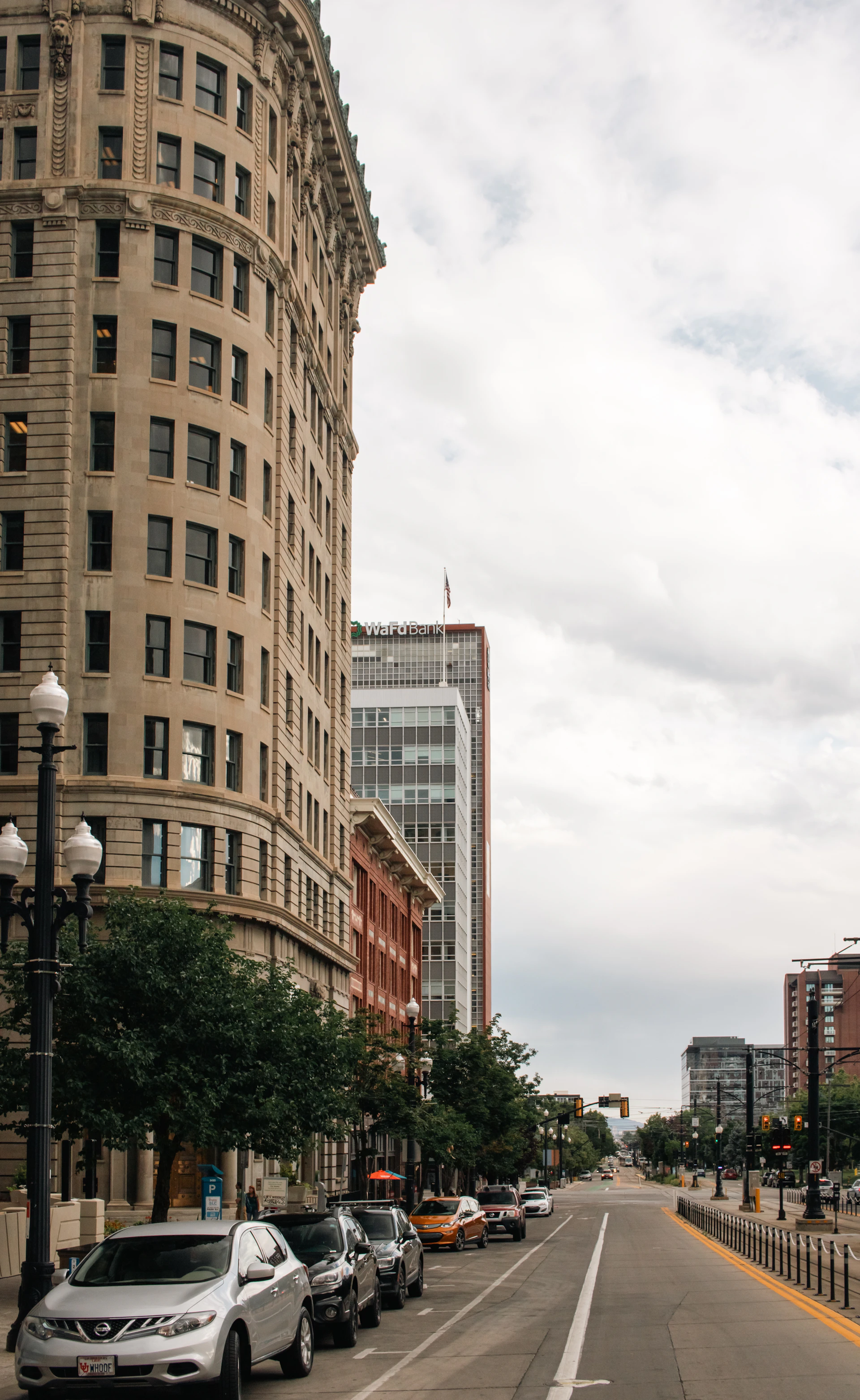 A city street lined with tall buildings and parked cars