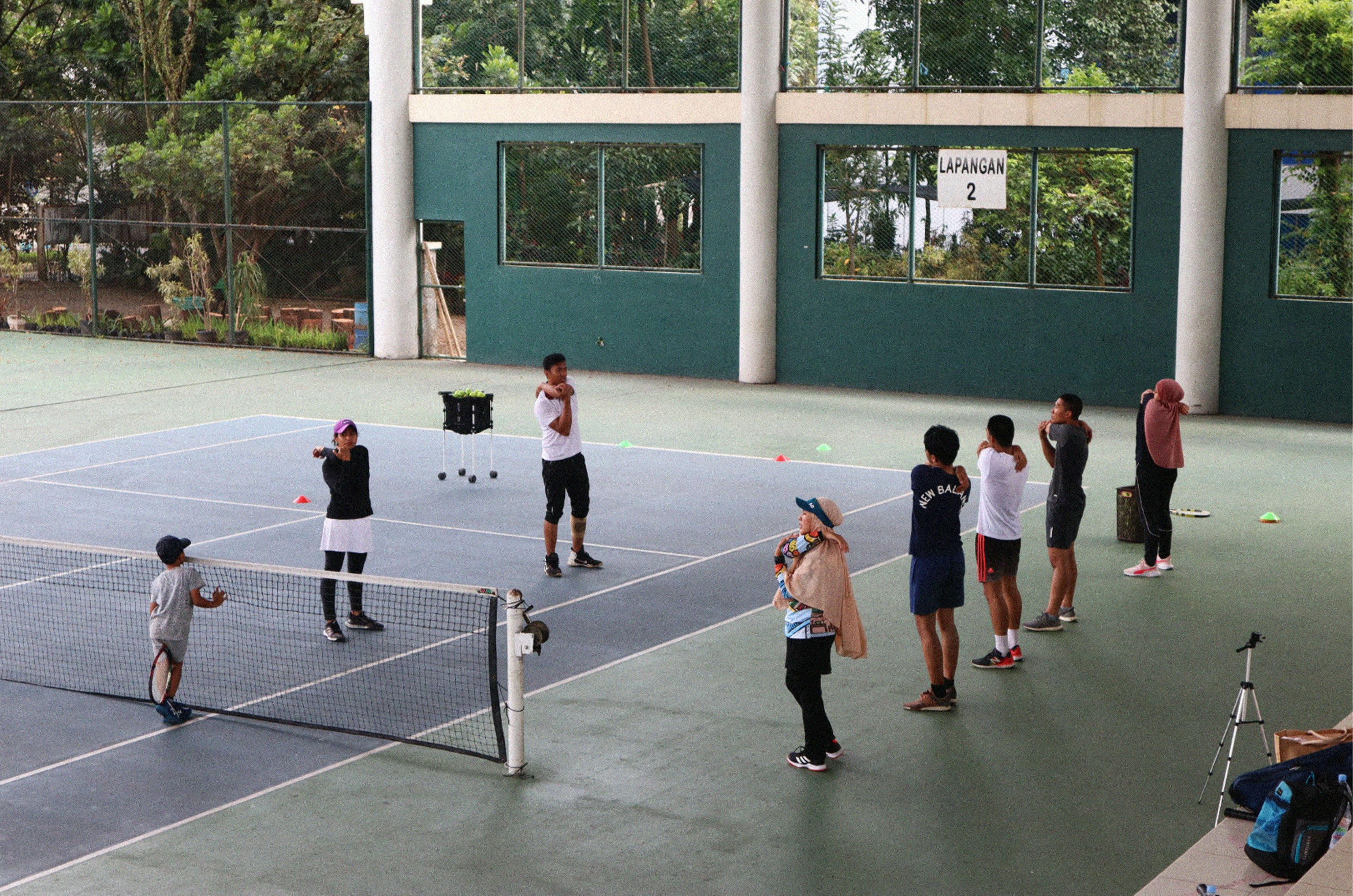 A group of people standing on top of a tennis court